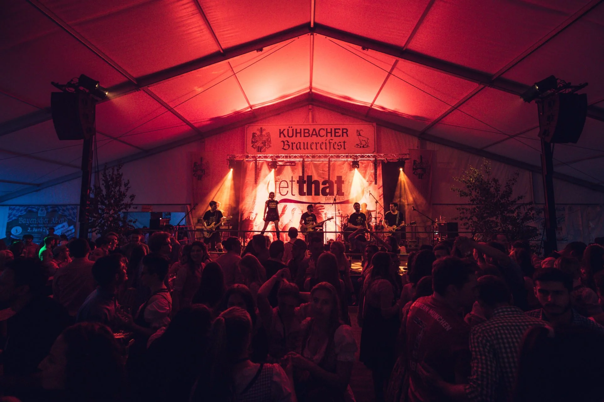 Musikband auf einer Bühne beim Brauereifest, Publikum tanzt und feiert im Festzelt mit bunten Lichtern.