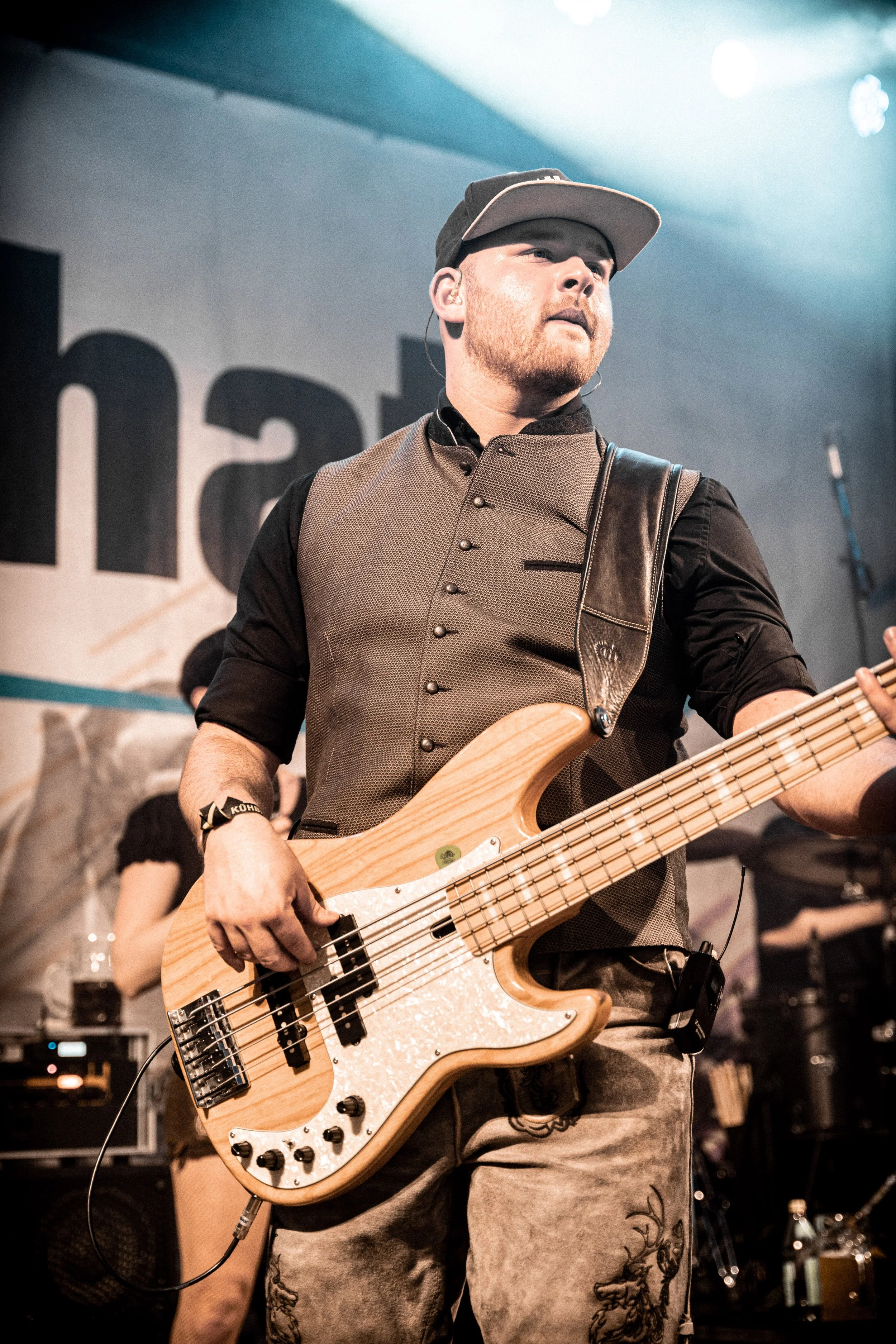 Ein junger Mann spielt Bassgitarre auf einer Bühne bei einem Konzert.