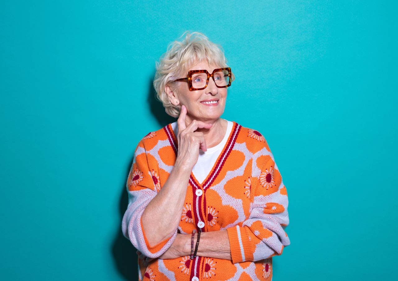 A brightly dressed senior woman looks happy and confident
