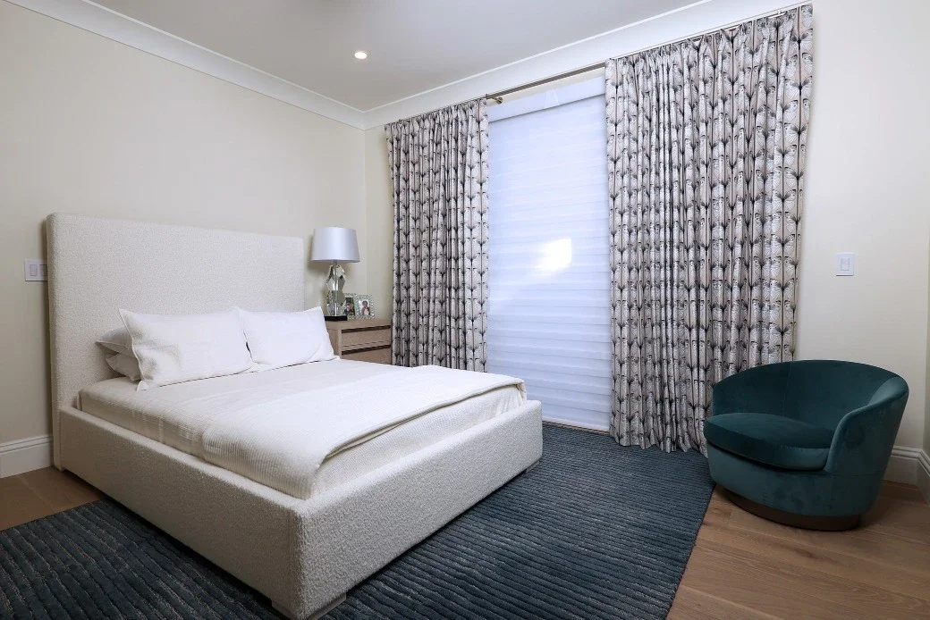 Custom, handmade butterfly-patterned drapes over motorized blinds in bedroom with green chair and rug