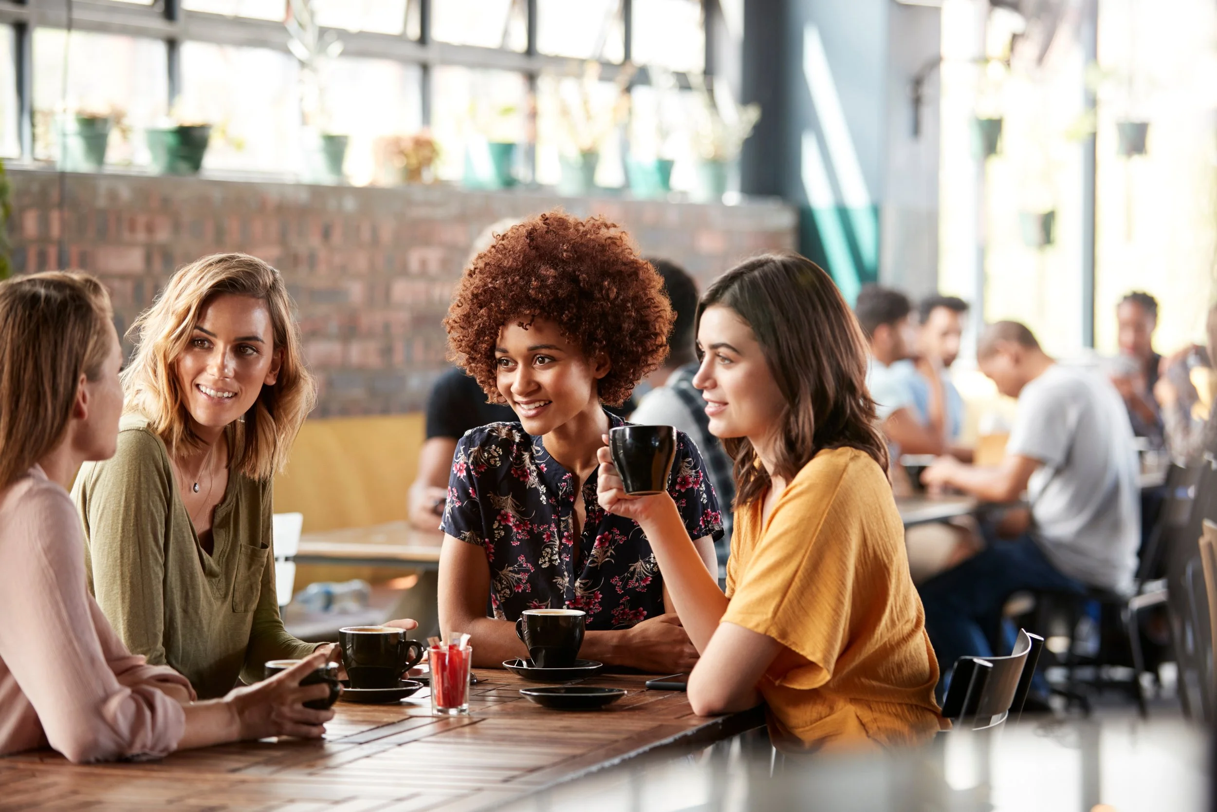 Four women having a conversation at a coffee shop