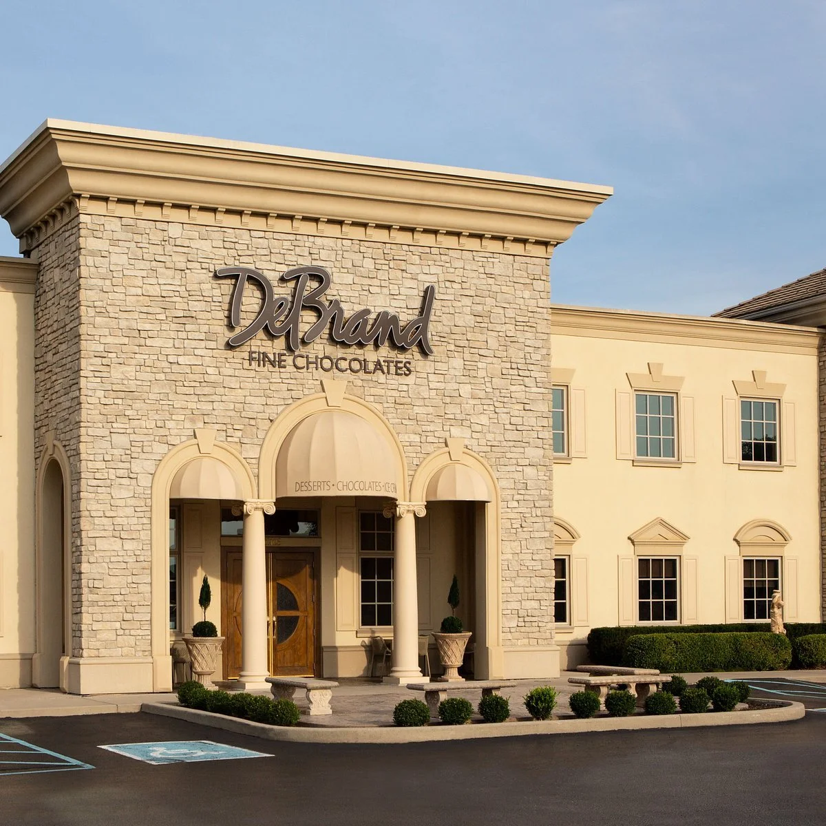 DeBrand Fine Chocolates storefront with beige stone facade, cream walls, and classic architectural details.