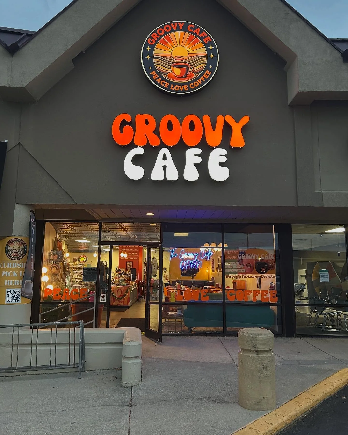 Exterior of Groovy Cafe with bright orange and white signage, glass doors revealing the cozy interior, and a neon sign that says 'The Groovy Cafe Open' inside.