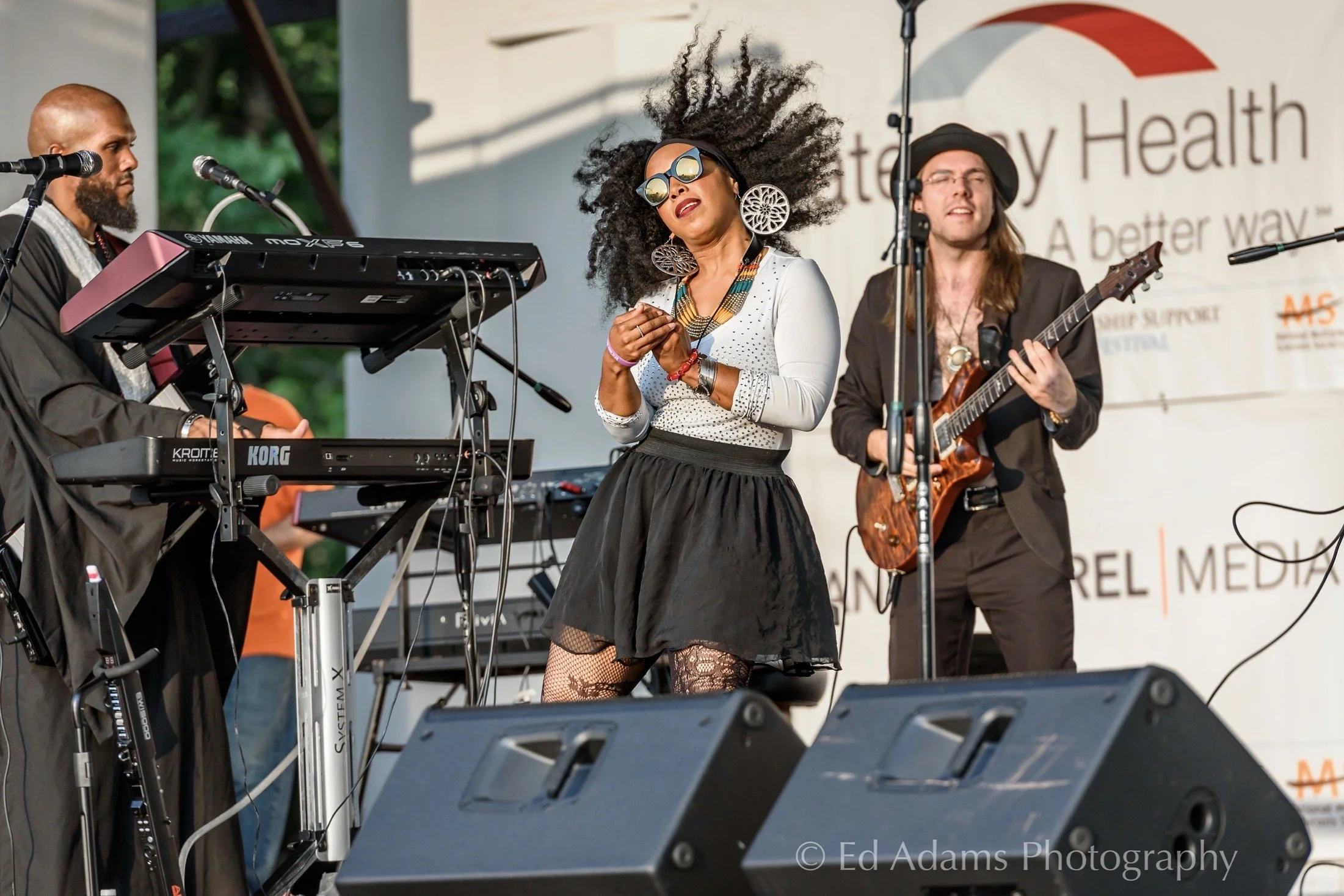 Musicians performing on stage with keyboards and guitar.