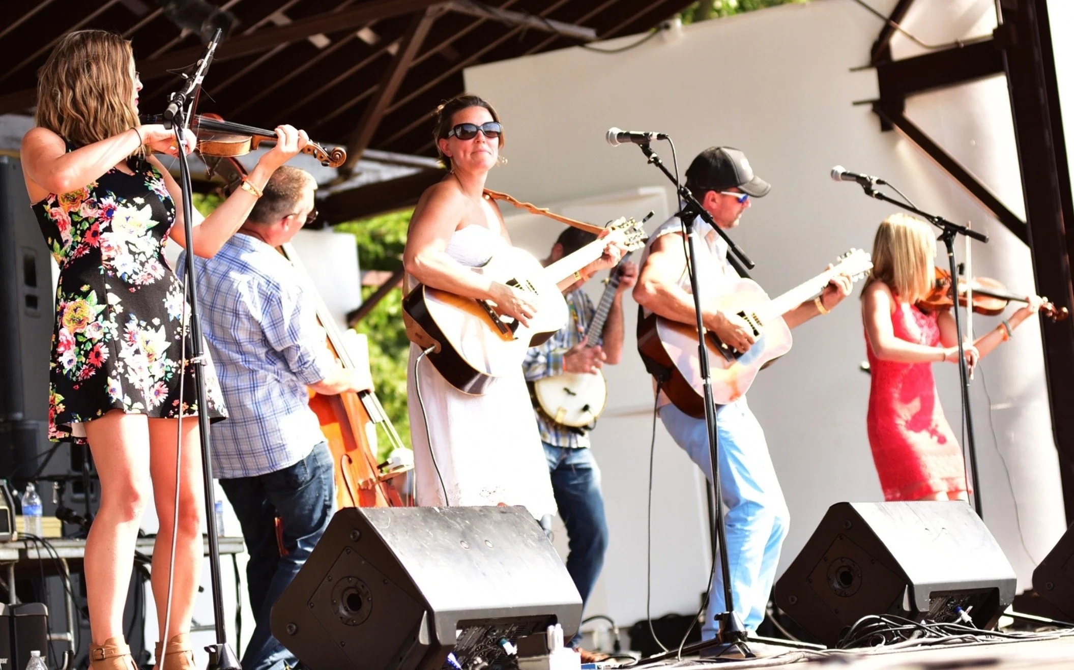 Band performing on an outdoor stage with two violinists, two guitarists, and a bassist.