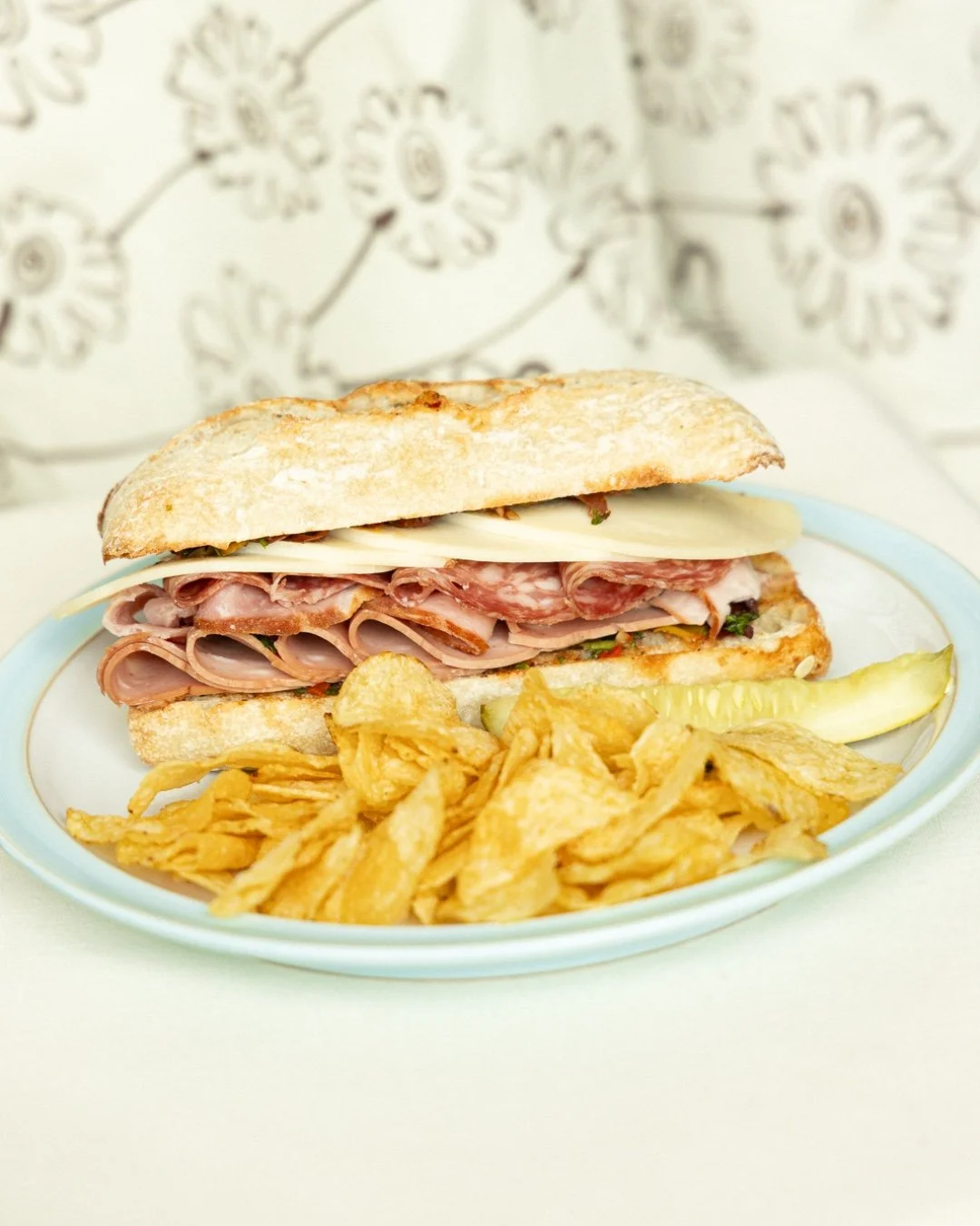 April is here, and so is something worth celebrating: we're bringing back the Muffuletta! 🫒💚 🥖
Made with house-made olive salad, ham, mortadella, genoa salami, and provolone, all melted on a demi-baguette. Served with your choice of a pickle &amp;