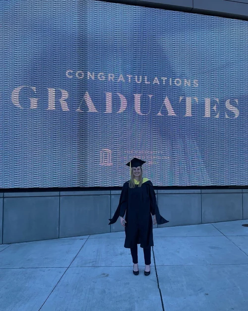 Image shows the author, Sarah Casteel, on her graduation day standing in front of a 'Congratulations Graduates' sign at UNC Chapel Hill. She graduated with a master's in Information Science.