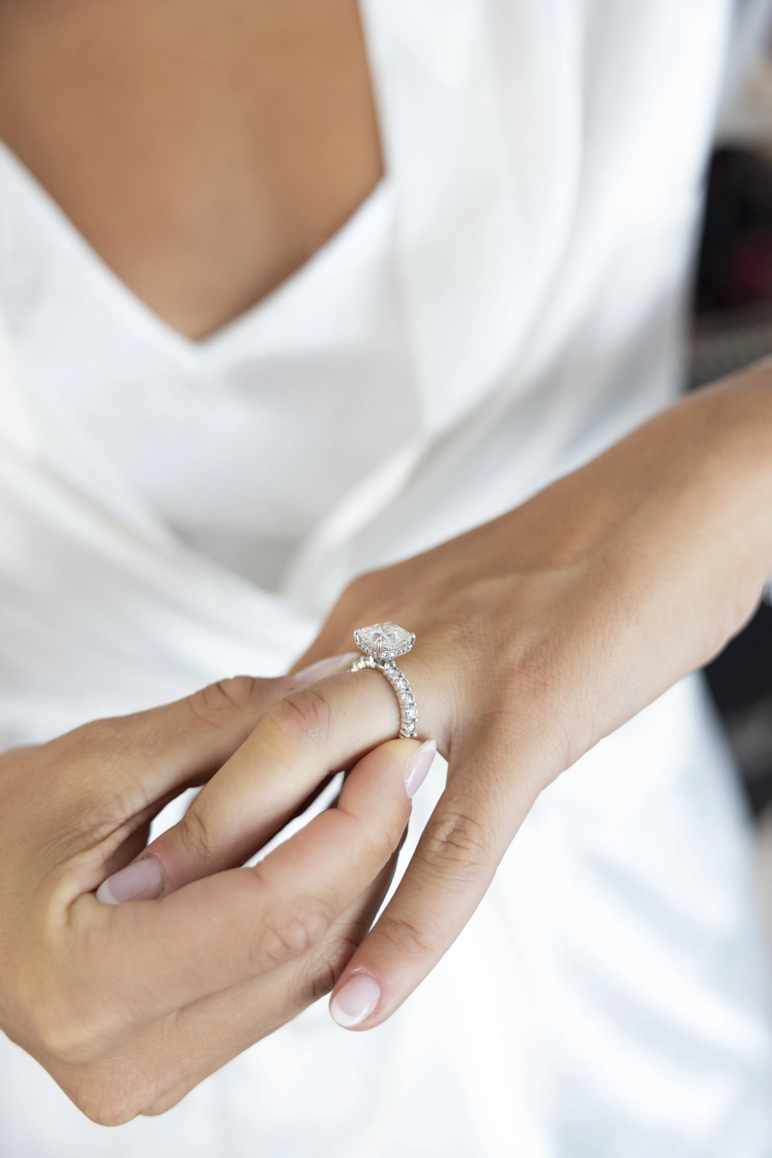 A person places a diamond engagement ring with a large center stone on another person's finger.