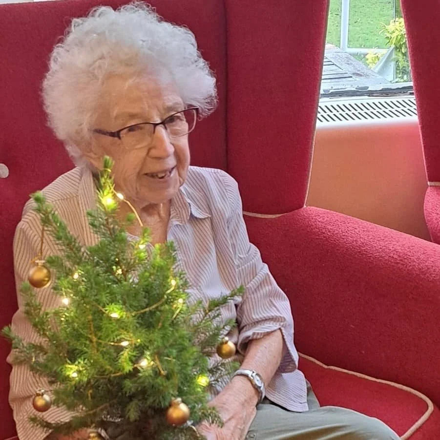 Mum, aged 97, sitting with her miniature Christmas tree