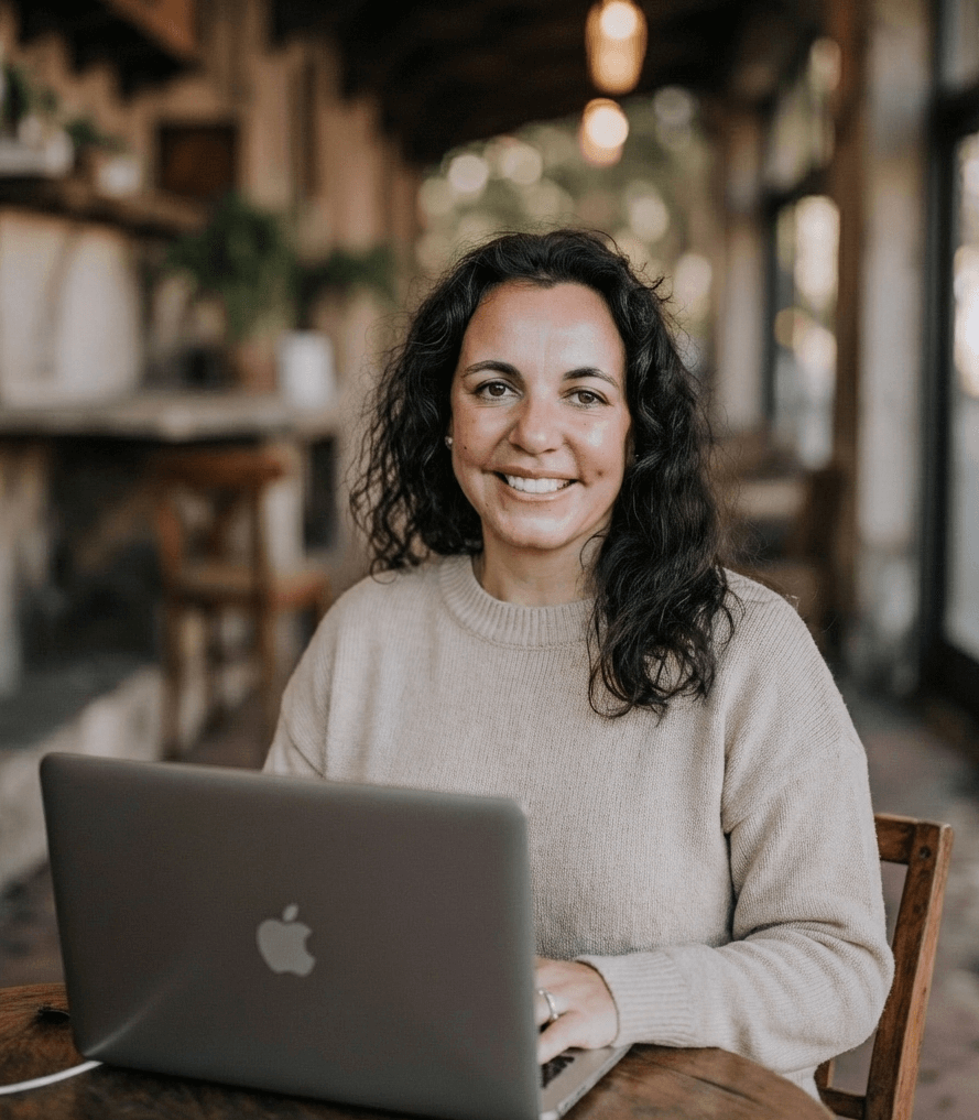 Susana Nikravesh owner and designer at YStrategize sitting at a table on her laptop.