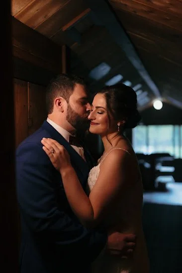 A newlywed couple sharing a romantic moment inside a wooden cabin with soft lighting.