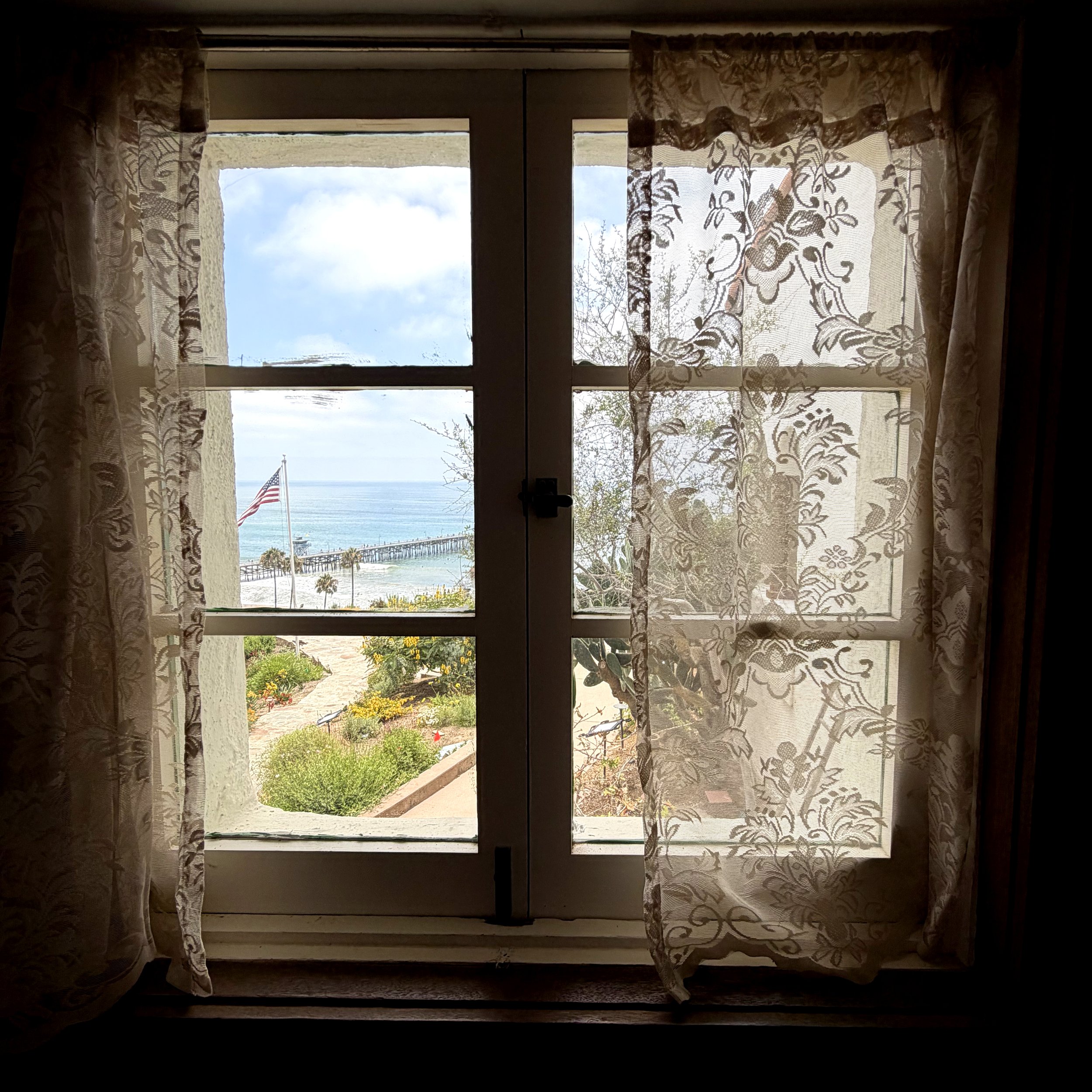 curtains over window looking out onto san clemente pier