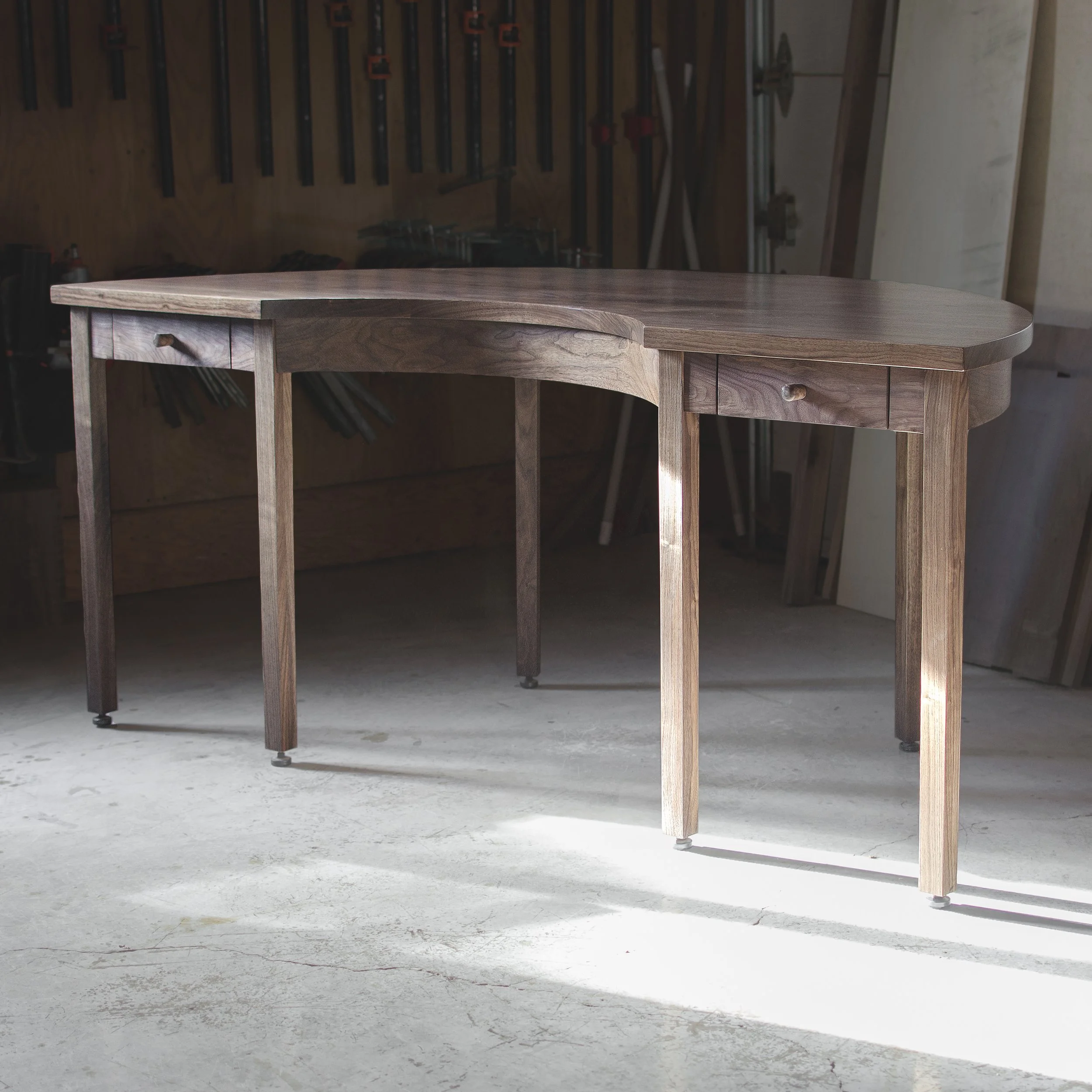 Table en bois dans un atelier de menuiserie, murs en bois avec outils accrochés.