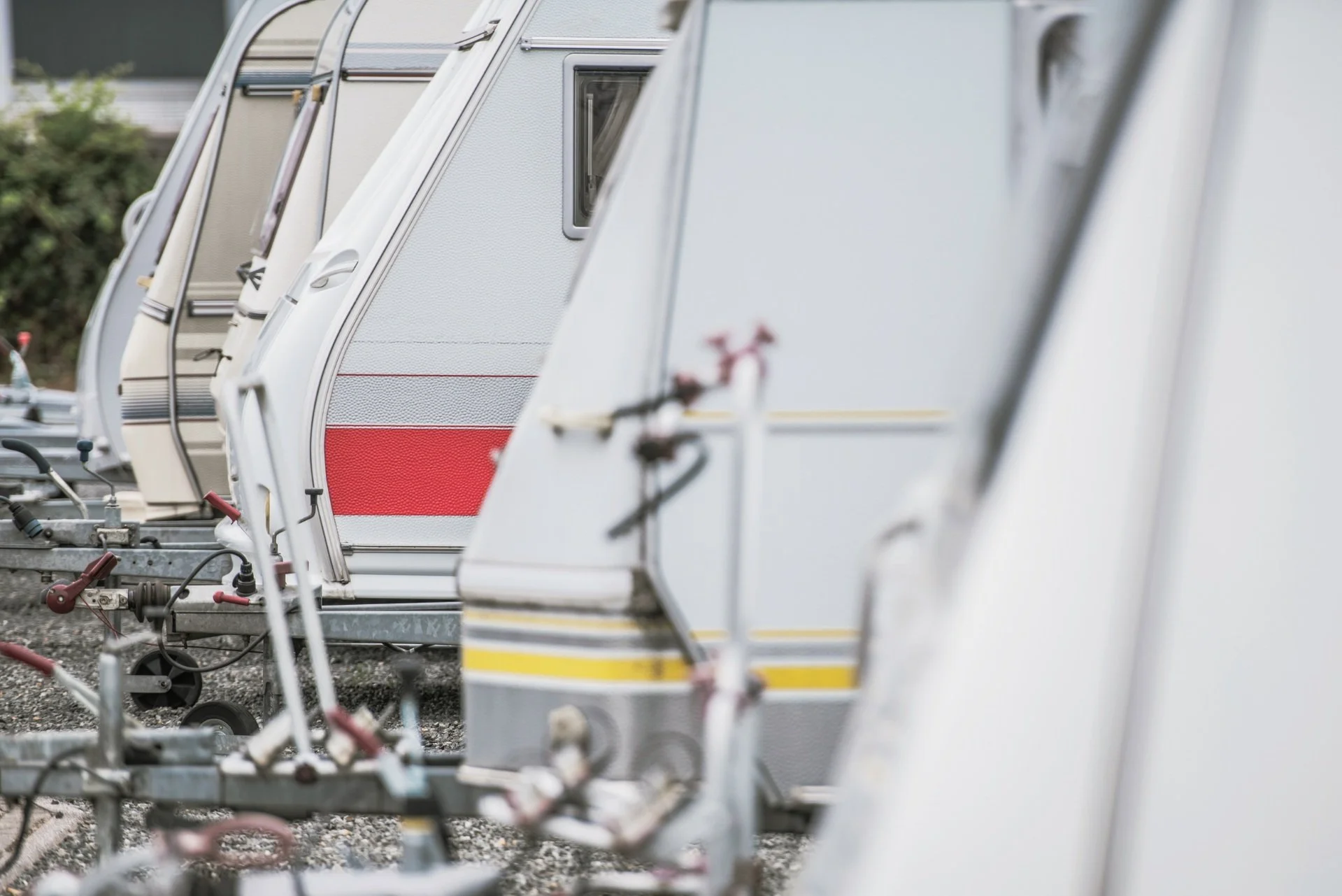 Several vintage travel trailers parked in a row, with focus on their sides, featuring various colors and stripe patterns.