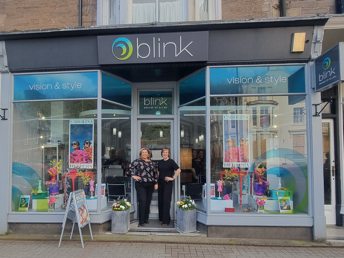Mandy and Laura, owners of Blink, Bridge of Allan standing outside the shop front with a beautiful window display of optical frames and sunglasses.