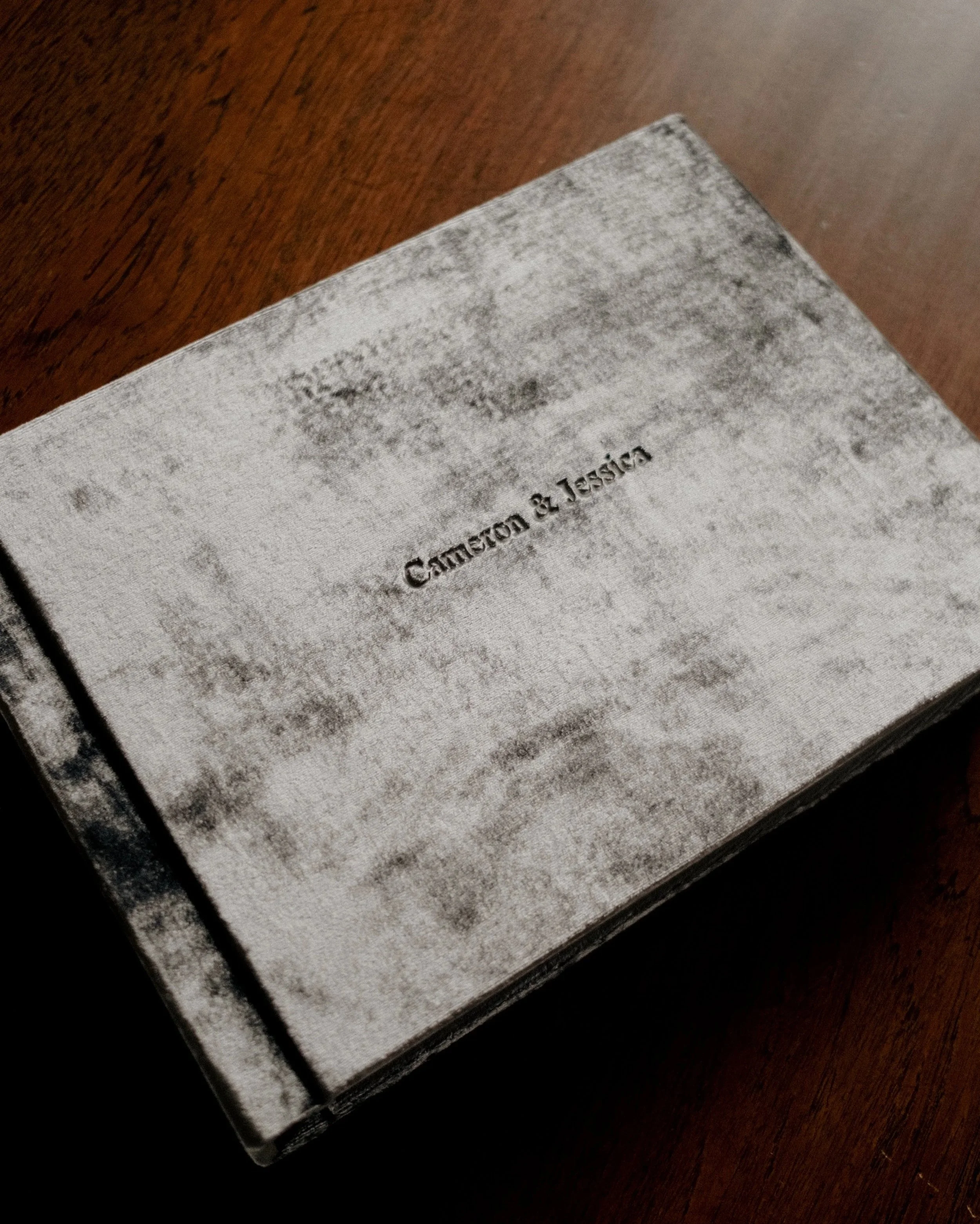 A book titled 'Cameron & Jersina' on a wooden surface, with a textured, weathered cover.