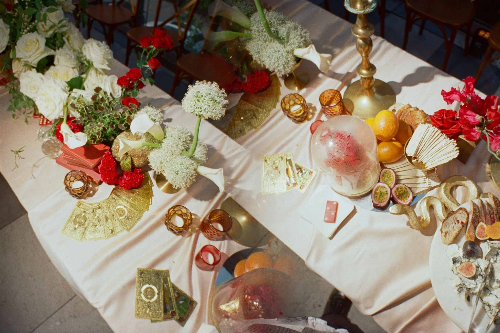 Table decorated with floral arrangements, candles, fruits, and desserts for a celebration or gathering.
