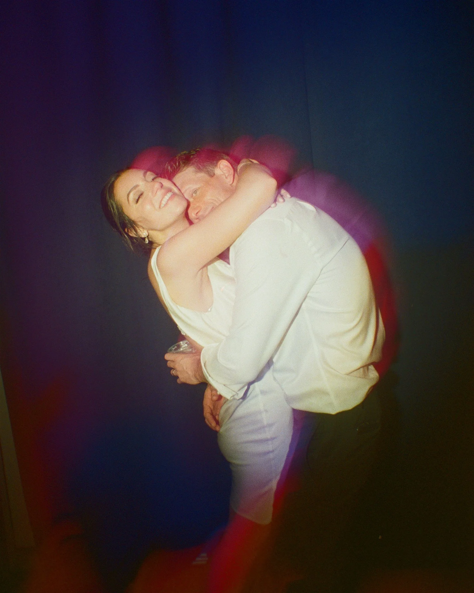 A man and woman hugging and smiling at each other at a joyful moment.