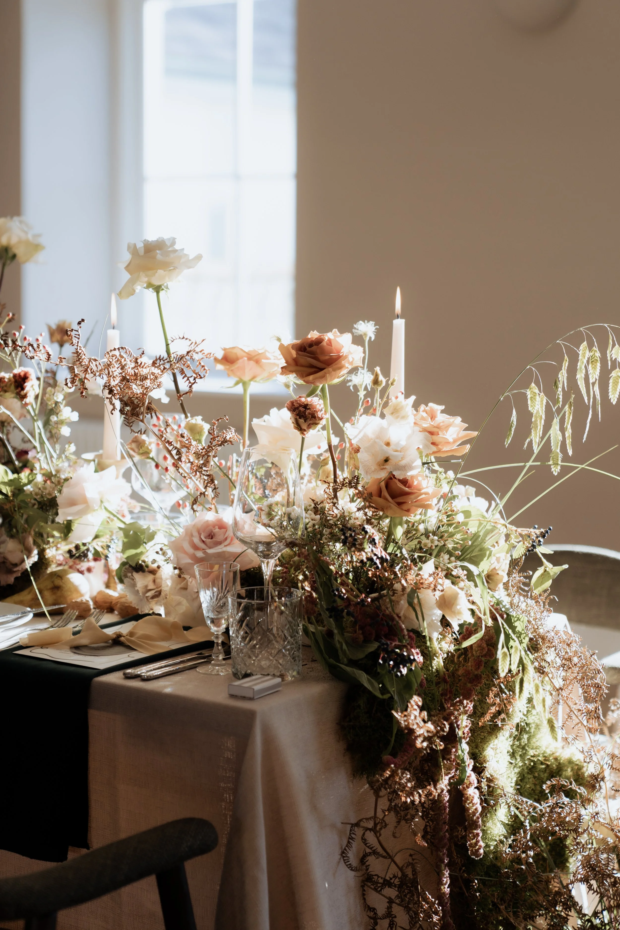 Luxurious floral tablescape with candlelight, textured linens and muted rose tones — elegant wedding styling perfect for high-end UK venues