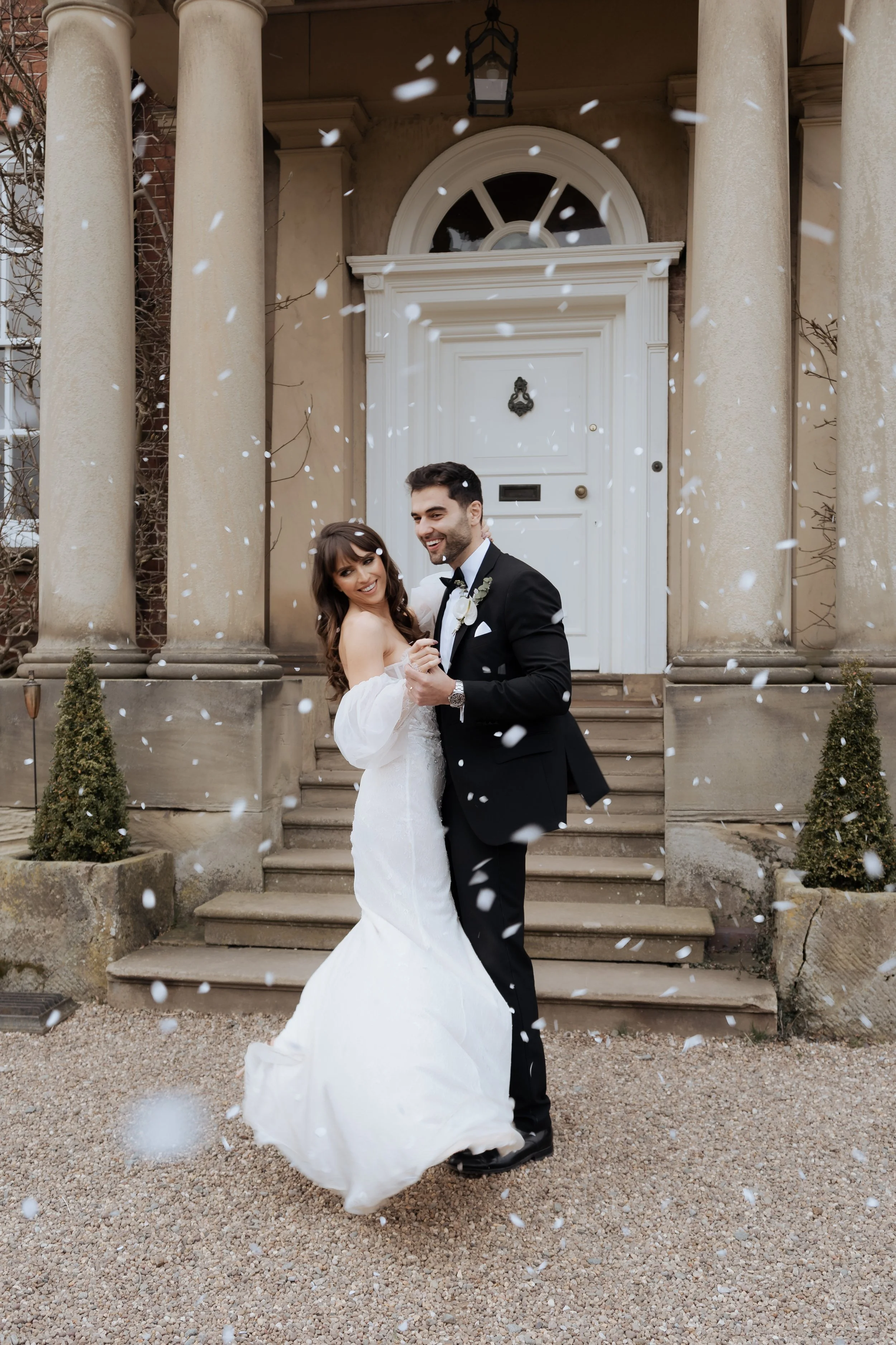 Bride and groom celebrating with confetti outside Iscoyd Park in Shropshire, captured in an elegant, editorial wedding photography style.