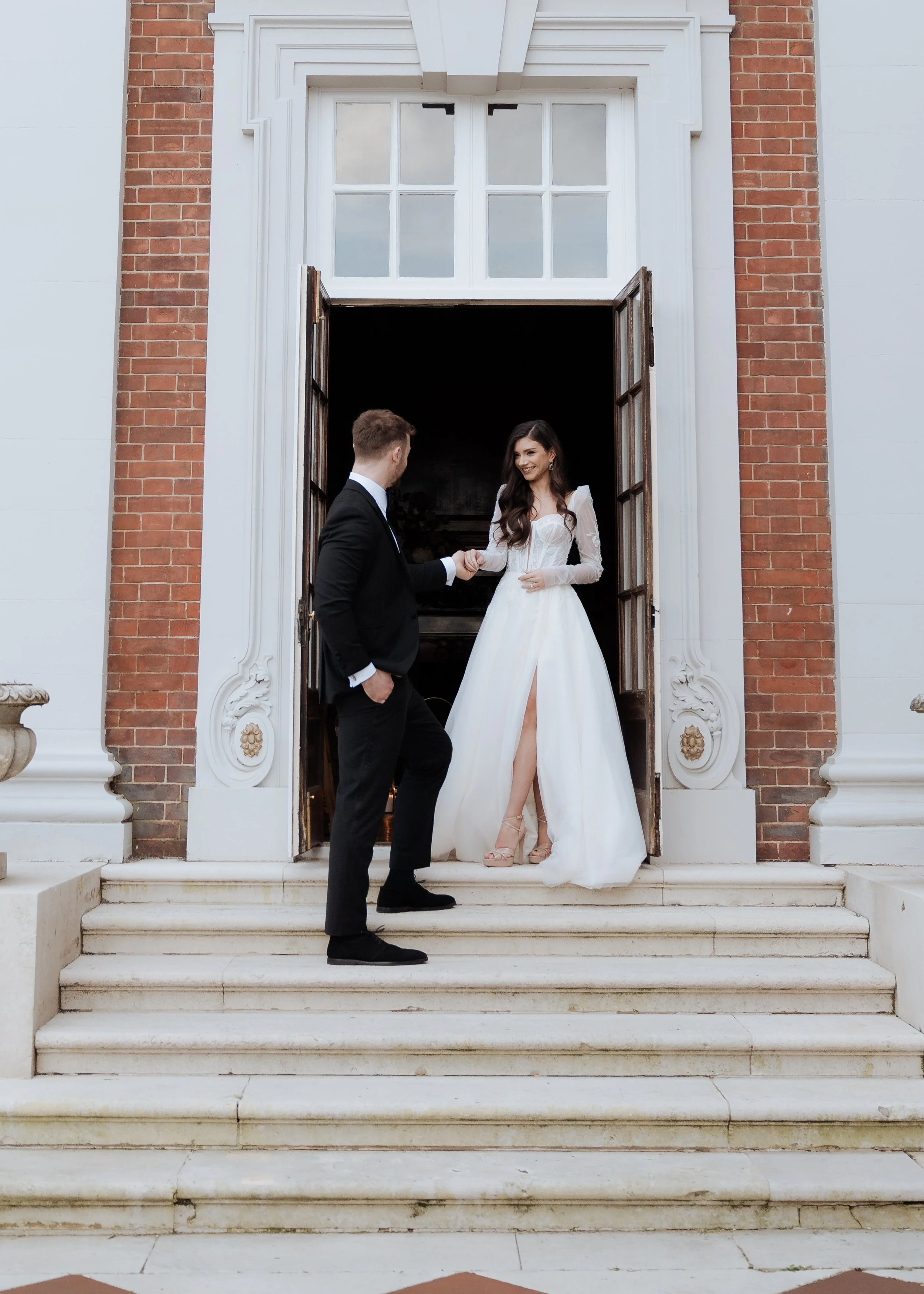Elegant couple stepping from a grand historic venue, photographed in a calm, editorial style inspired by luxury wedding venues such as Hawkstone Hall in Cheshire.