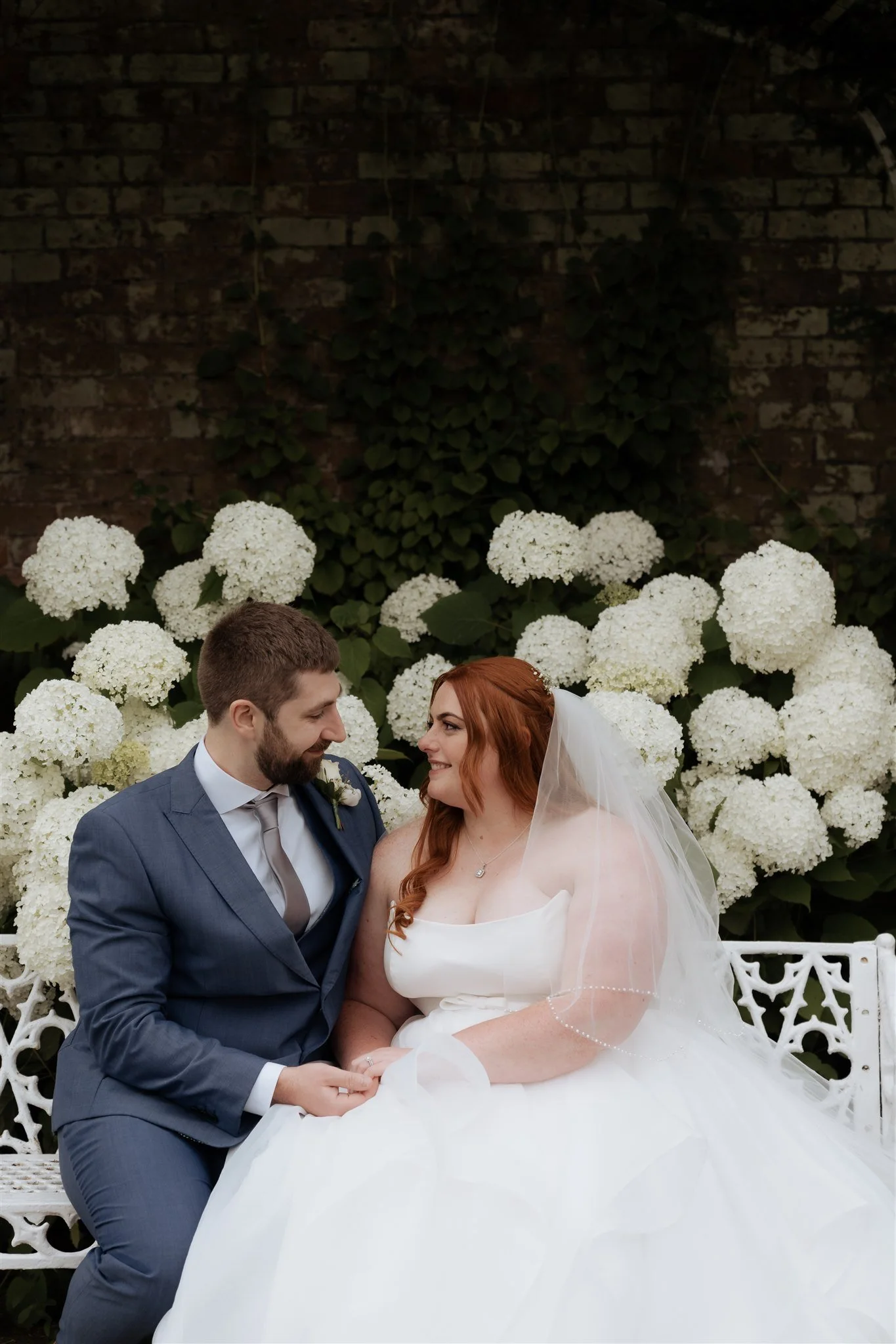 Bride and groom portraits in the gardens at Combermere Abbey surrounded by elegant white hydrangeas