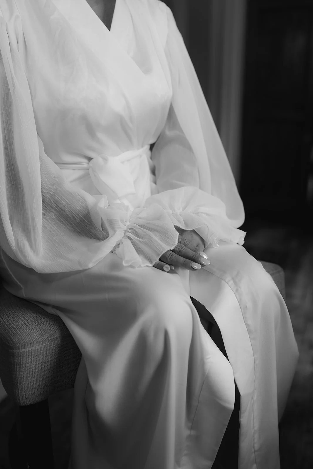 Black and white bridal detail photograph showing soft fabric and hands at rest, captured in a quiet moment by Cleo Stella, editorial wedding photographer working across Cheshire and Shropshire.