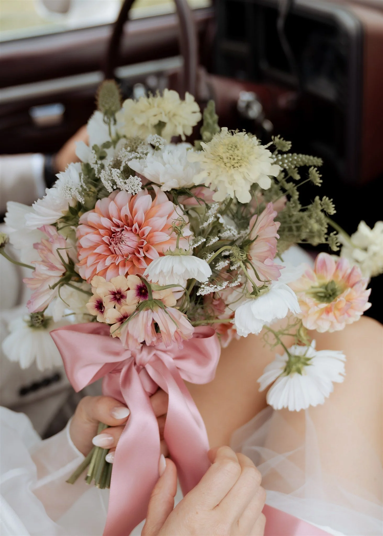 An editorial floral detail capturing soft, romantic blooms and flowing ribbon. Photographed with a fashion-inspired eye, this image focuses on texture, colour and artistry, complementing a timeless, modern wedding aesthetic.