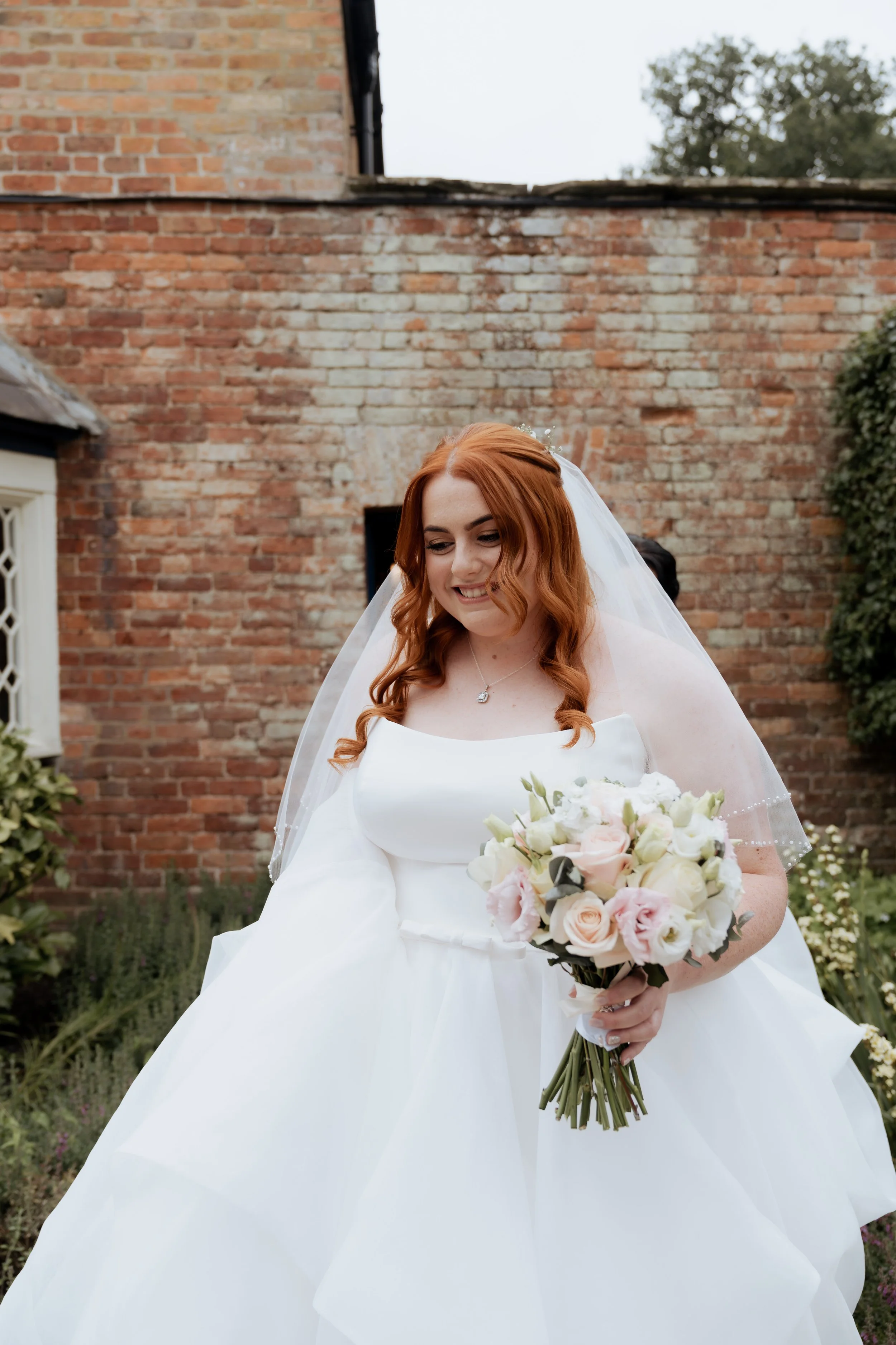 Intimate wedding moment at Combermere Abbey with a bride walking out of a brick doorway, photographed by Cleo Stella Photography.