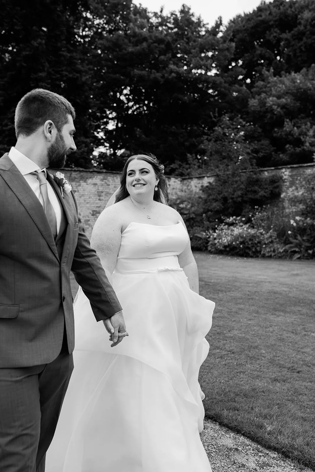 Black and white wedding portraits at Combermere Abbey featuring a modern couple walking through the gardens