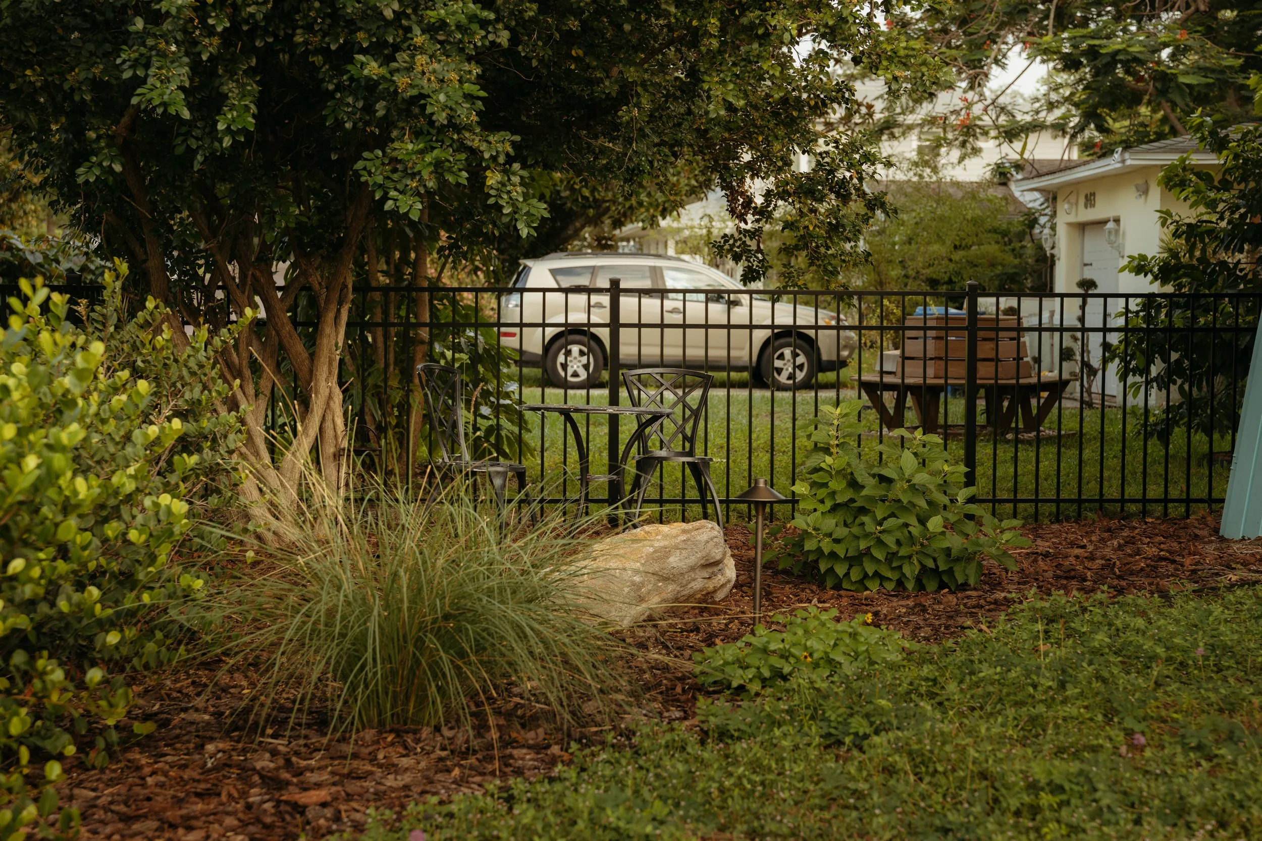 Corner seating area in front yard garden design and installation with Florida native plants, ground cover, and boulders