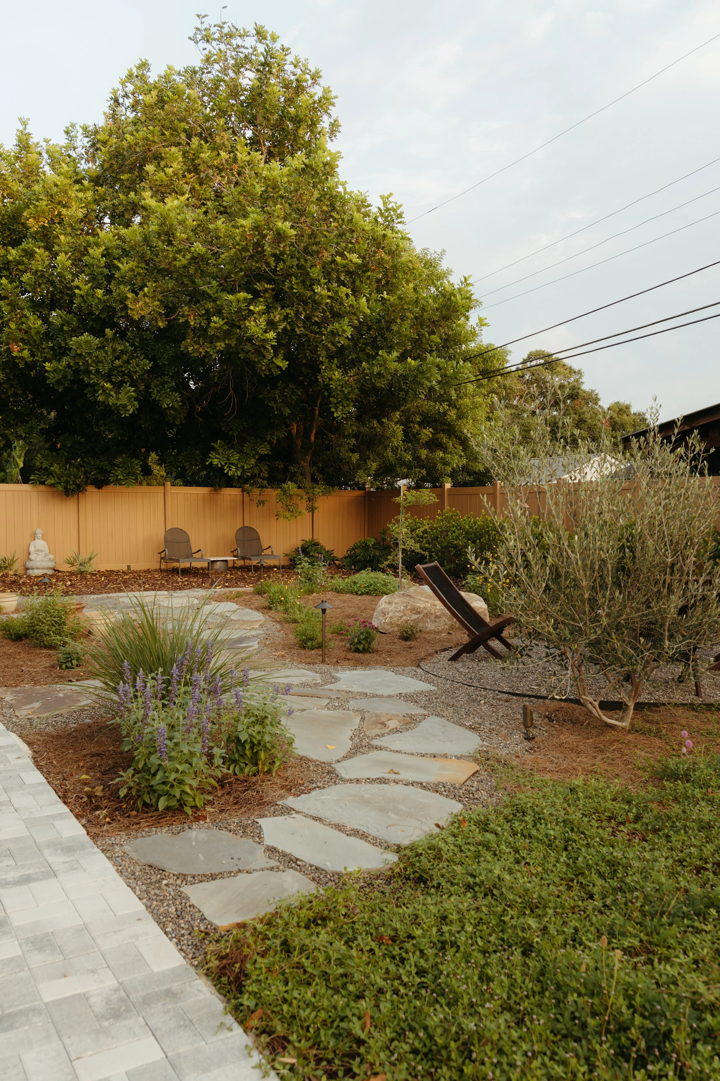 back yard garden design and installation with a boulders, flagstone, pathway lighting, Florida native plants, and flowers, purple, olive, sage color tones