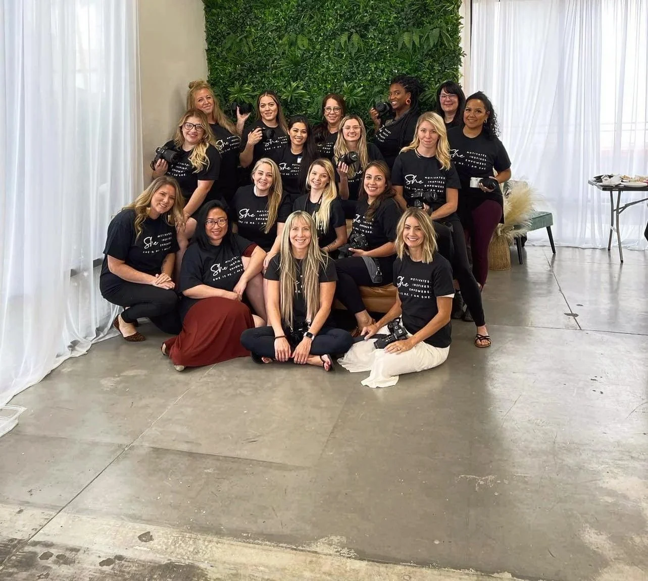 A large group of female photographers posing together at a learning workshop event in a bright studio.