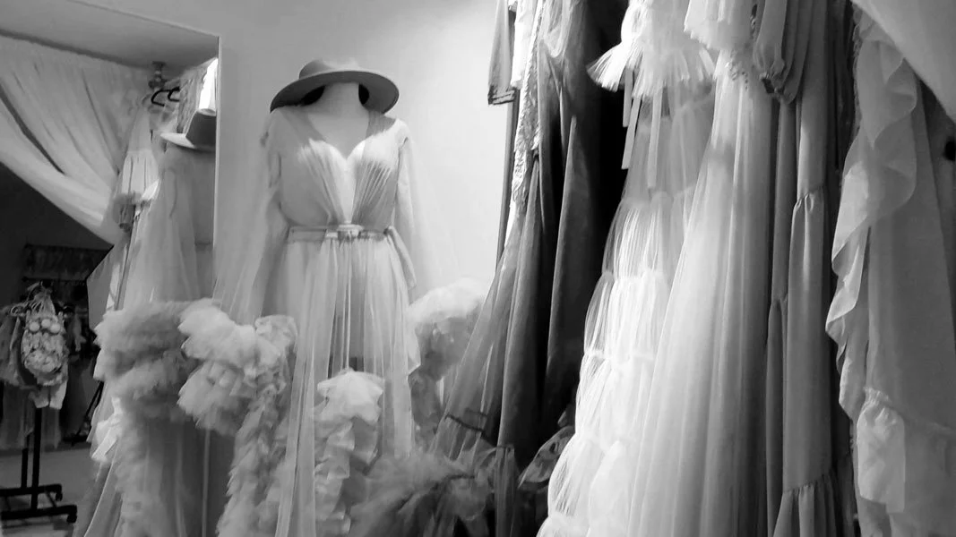 Black and white view of a luxury maternity client closet in West Linn, Oregon, featuring a curated selection of high-end couture gowns and tulle skirts for premium portrait wardrobe options.