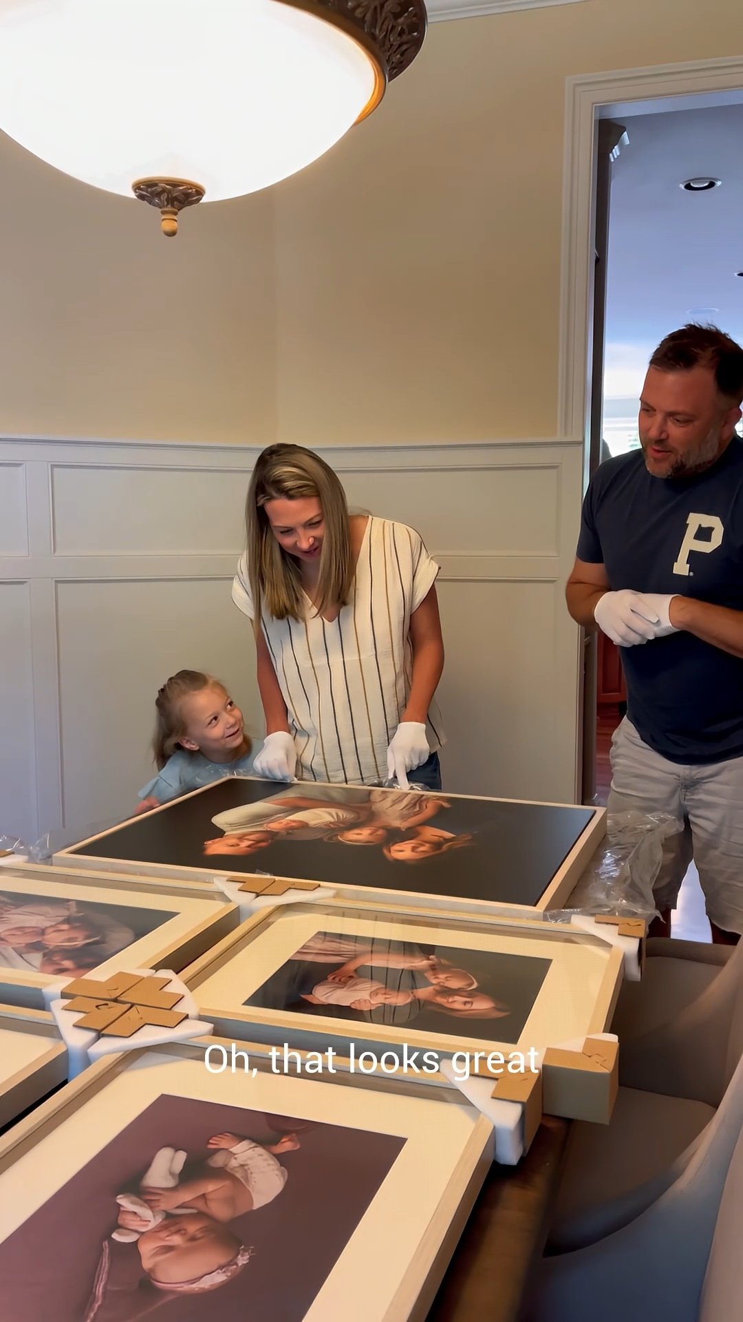 This image highlights the "reveal" stage of a luxury portrait experience, where families in the Portland metro area see their finished milestones transformed into tangible art. The photograph captures a candid moment of discovery as a family unboxes 