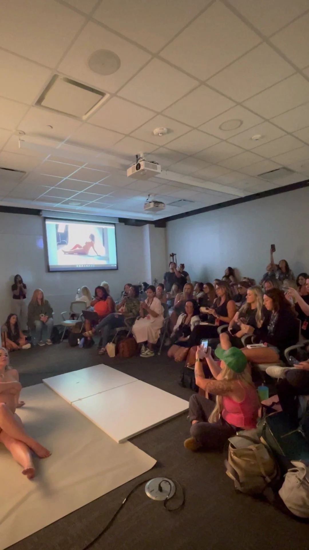 Professional photography seminar featuring a live maternity posing demonstration and projector presentation.