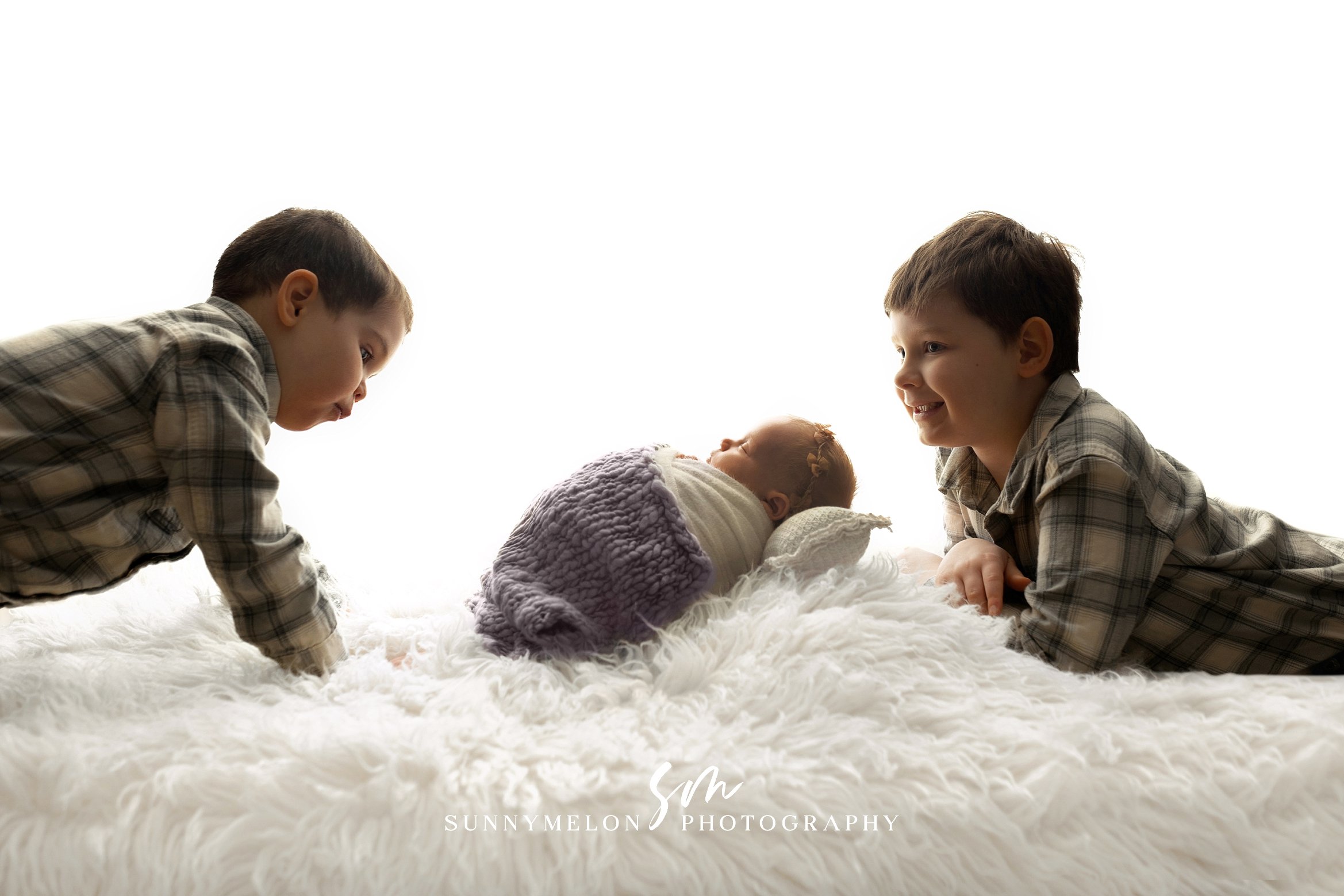 Sibling looking at newborn baby during Portland Oregon studio photography session