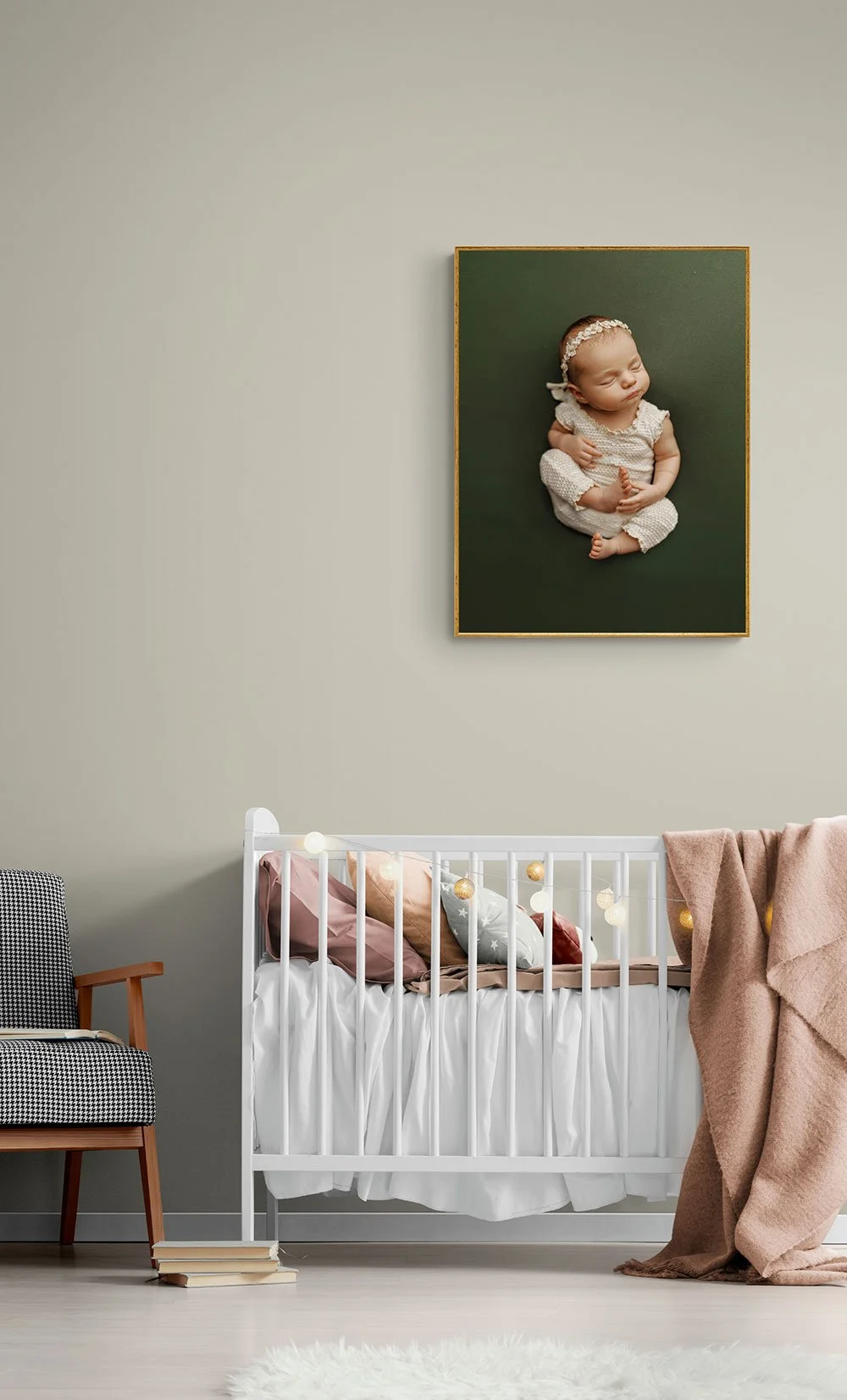 Gold framed vertical fine-art newborn portrait on a forest green backdrop mockup hanging on a neutral nursery wall above a white crib.