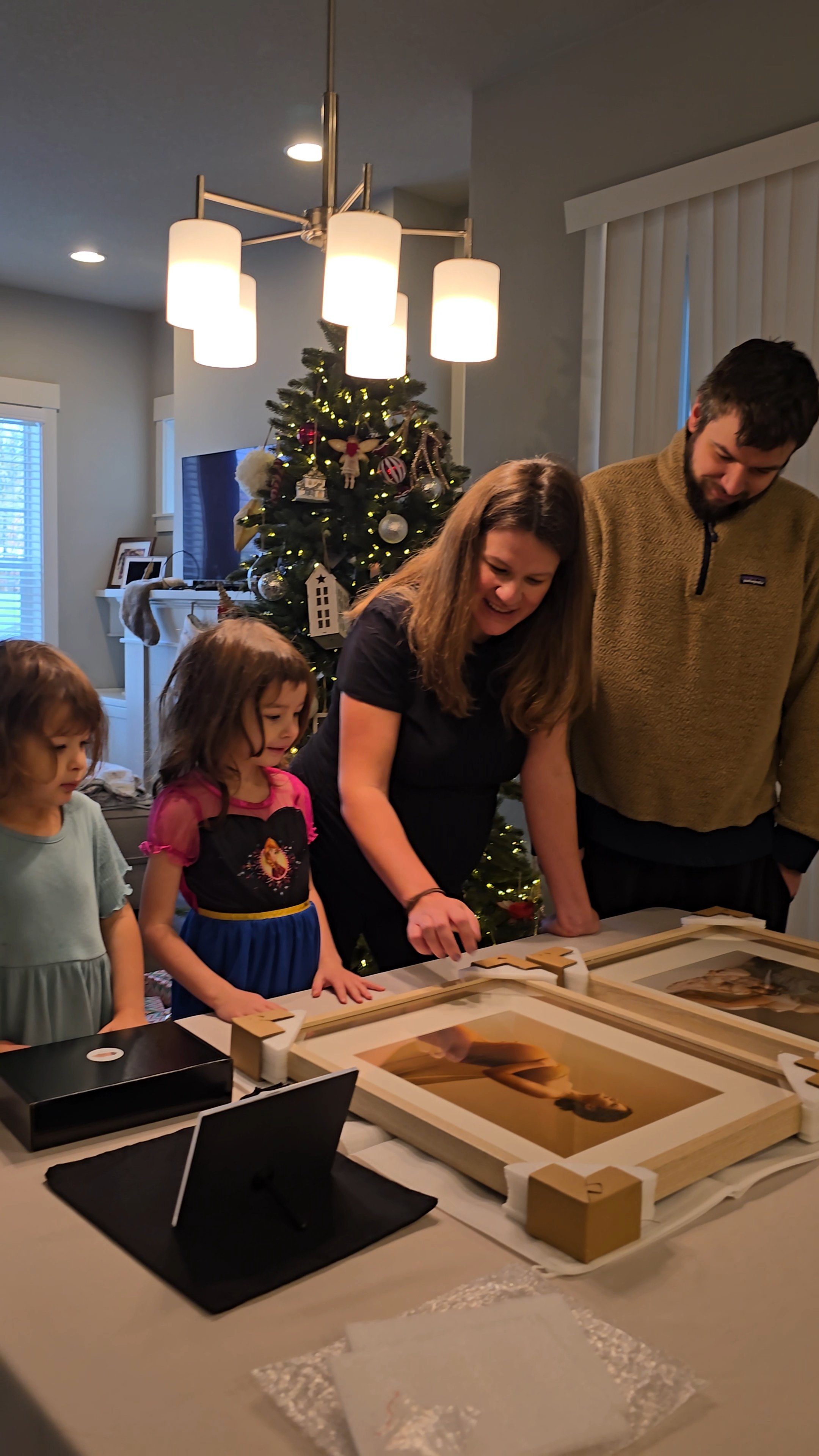 This image highlights the emotional and tangible conclusion of a full-service portrait experience, where a family in Portland views their finished heirloom wall art for the first time. The scene features a mother and father along with their children 