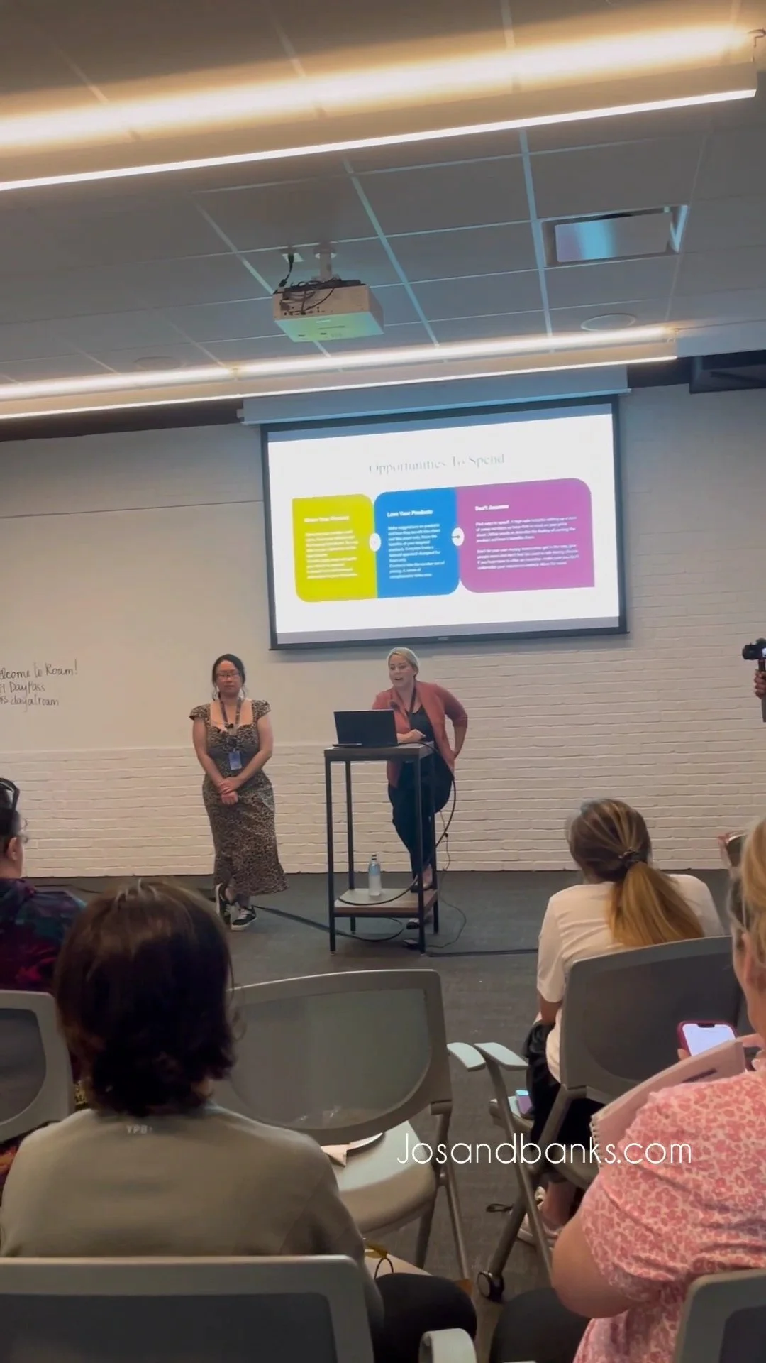 Two women presenting a business strategy seminar for photographers at a professional conference.