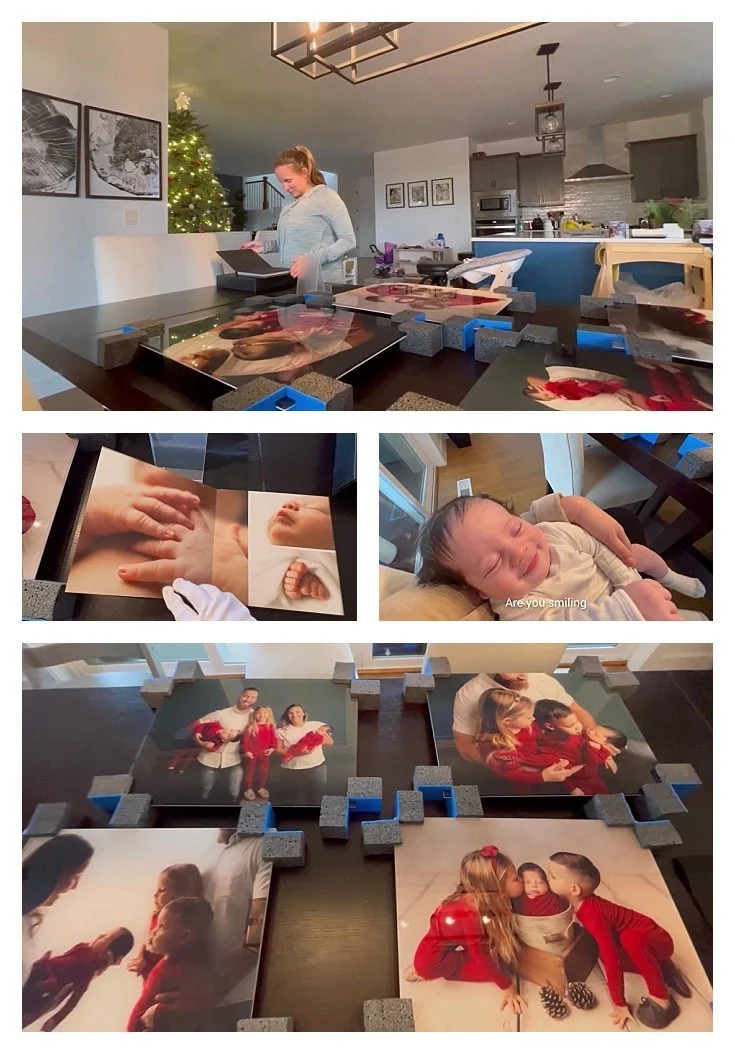 Mother unboxing large acrylic wall art prints of Christmas family portraits on a dining table.
