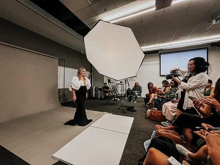 Photographer Josie Tan demonstrating professional lighting and posing techniques with a maternity model during a live Jos and Banks workshop for a group of students.