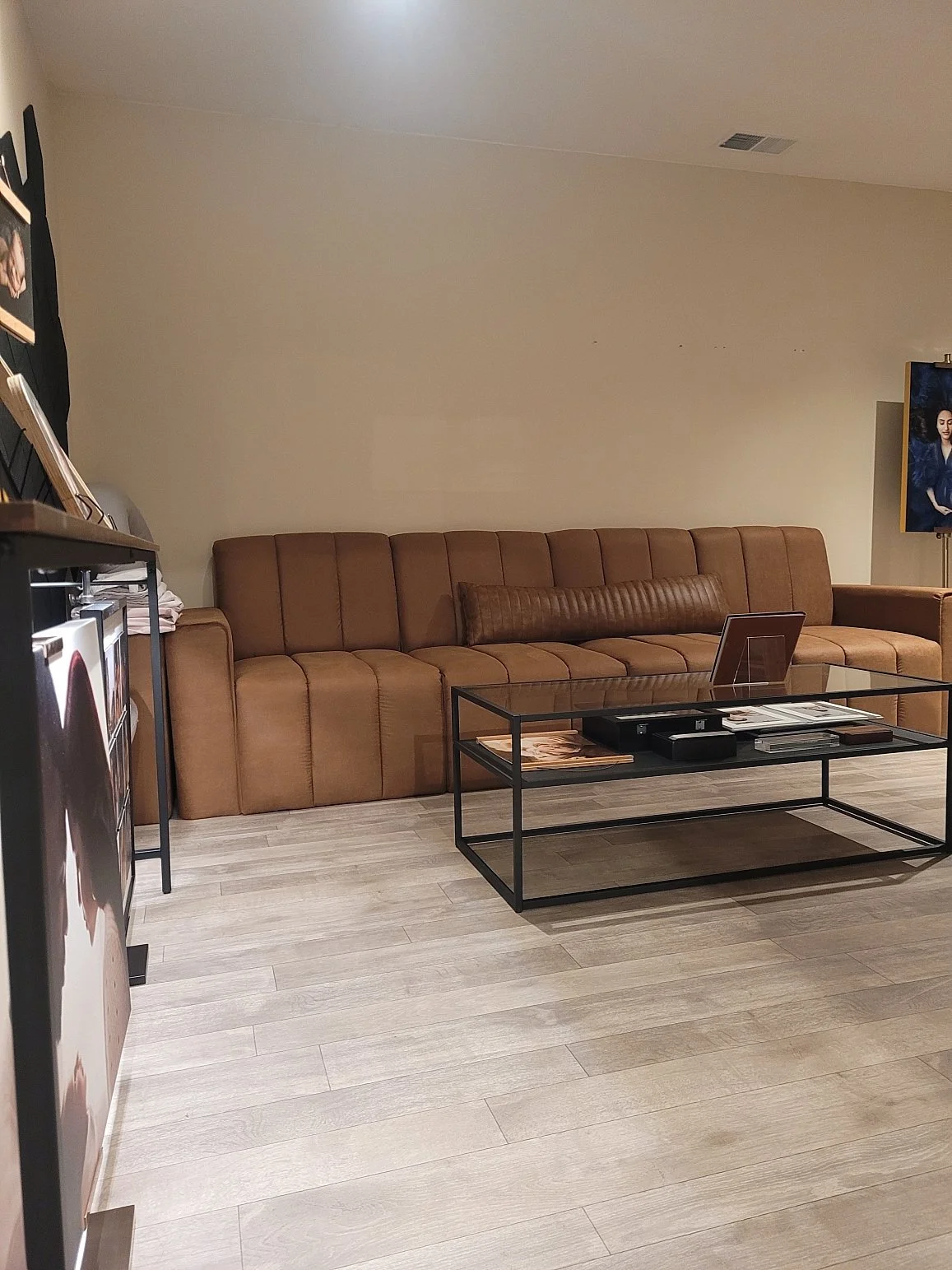 Interior view of the Sunny Melon Photography studio in West Linn, Oregon, featuring a modern tan channel-tufted sofa, glass coffee table, and professional portrait displays.