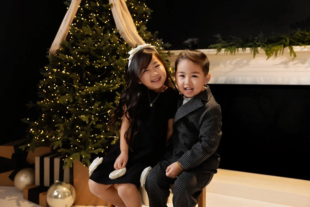 A joyful young girl and boy posing together during a holiday studio session in Portland.