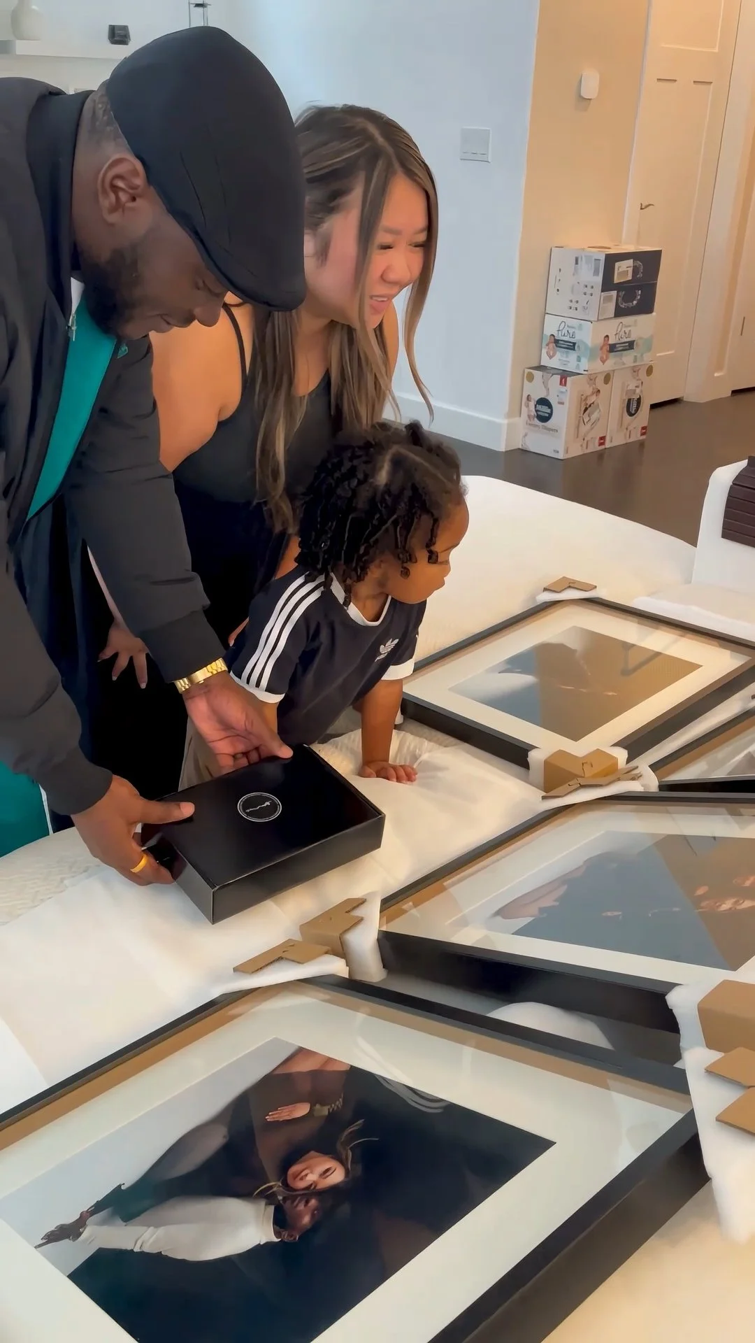 This image highlights the "reveal" stage of a luxury portrait experience, where families in the Portland metro area see their finished milestones transformed into tangible art. The photograph captures a candid moment of discovery as a family unboxes 
