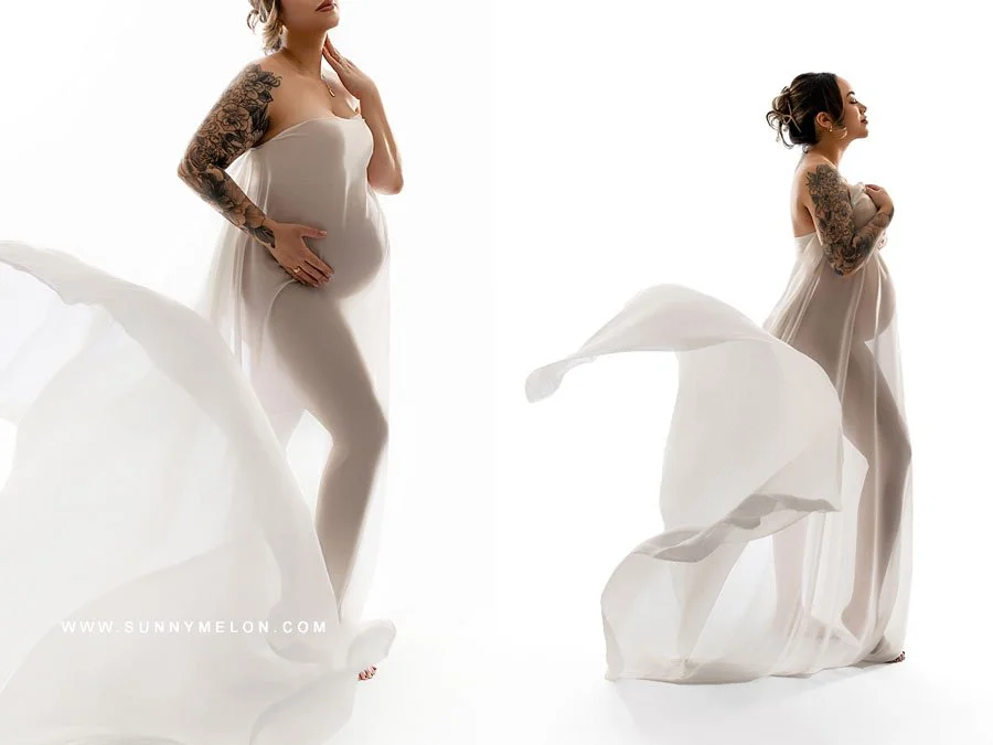A side-profile maternity portrait of a woman draped in sheer white silk fabric, standing against a bright white backlit background to create a soft, ethereal silhouette.