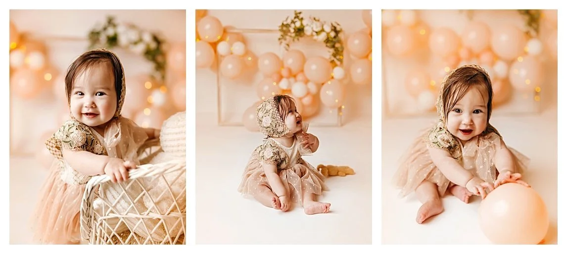 A three-image collage of a one-year-old baby girl in a lace dress and matching bonnet; featuring her sitting next to a white wicker bassinet, looking up at a peach balloon arch, and playing with a balloon in a cream-colored studio.