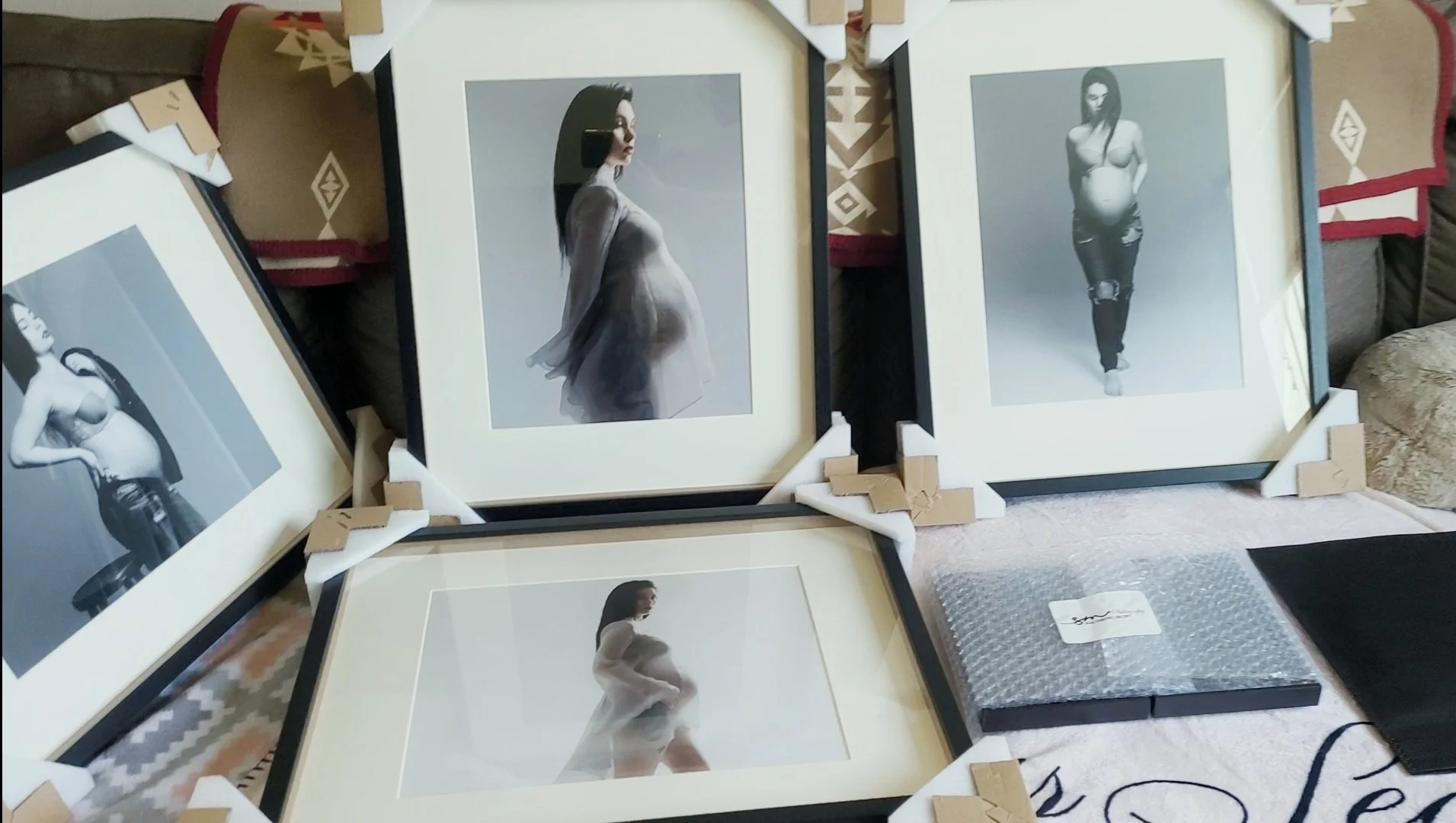 This image showcases a curated collection of fine art maternity photography, emphasizing the transition from digital session to a custom-framed gallery. The four large portraits are matted and framed in elegant black, still featuring protective foam 