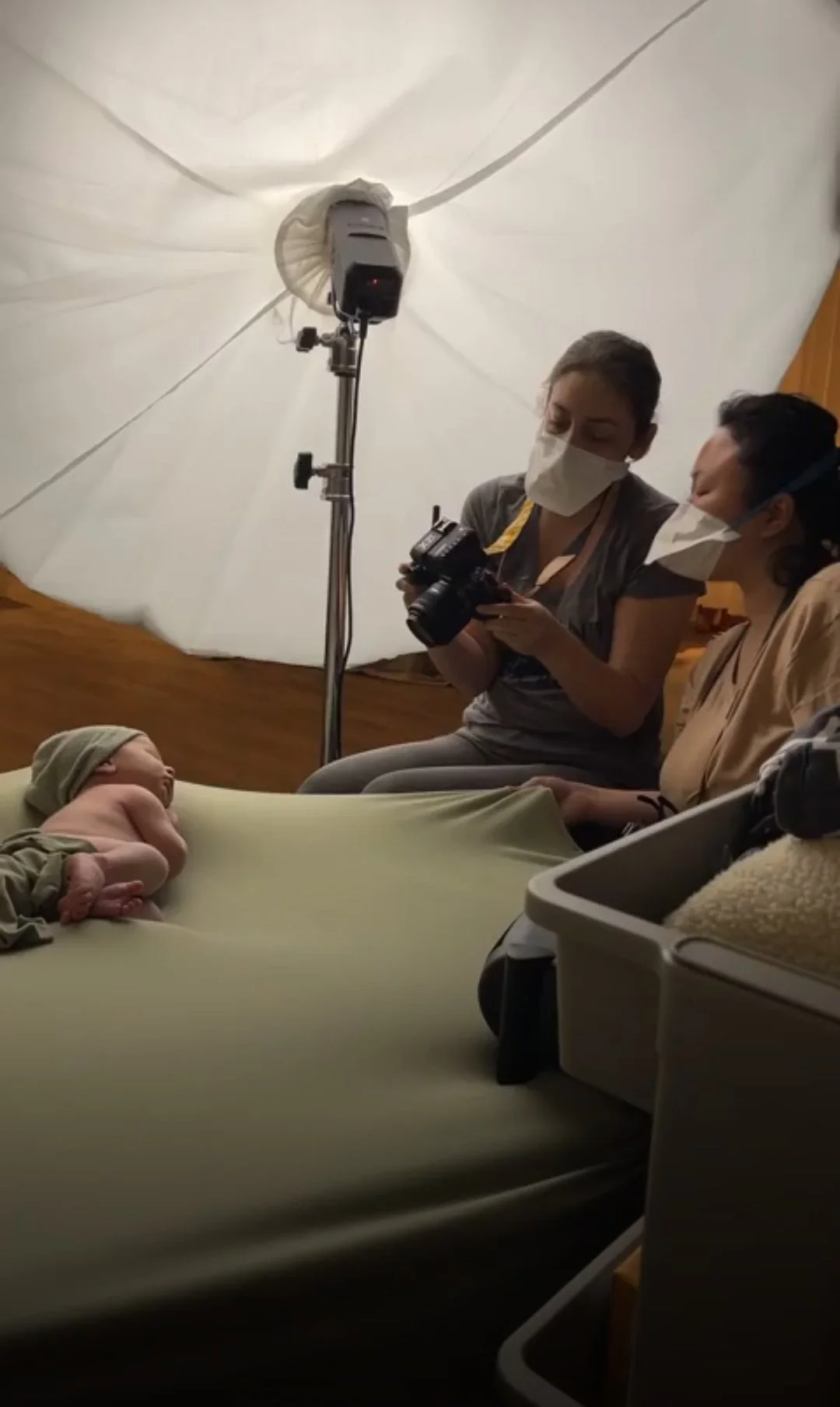 Professional newborn photographers reviewing shots on a camera during a studio session with an infant.