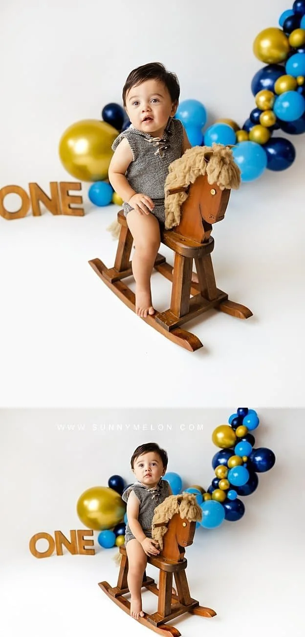 Toddler boy in vintage overalls posing with a wooden rocking horse in a rustic studio set.